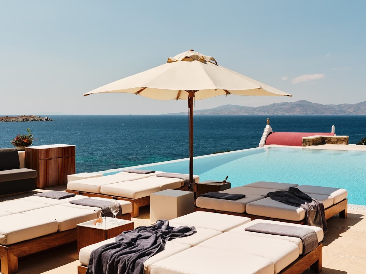 The clifftop infinity pool at Bill&Coo above Megali Ammos beach, Mykonos, lit at dusk