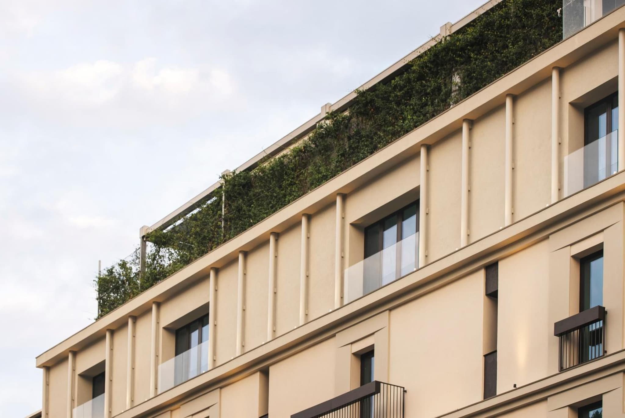 The pale exterior facade of Europa Palace featuring glass balconies and a rooftop garden.