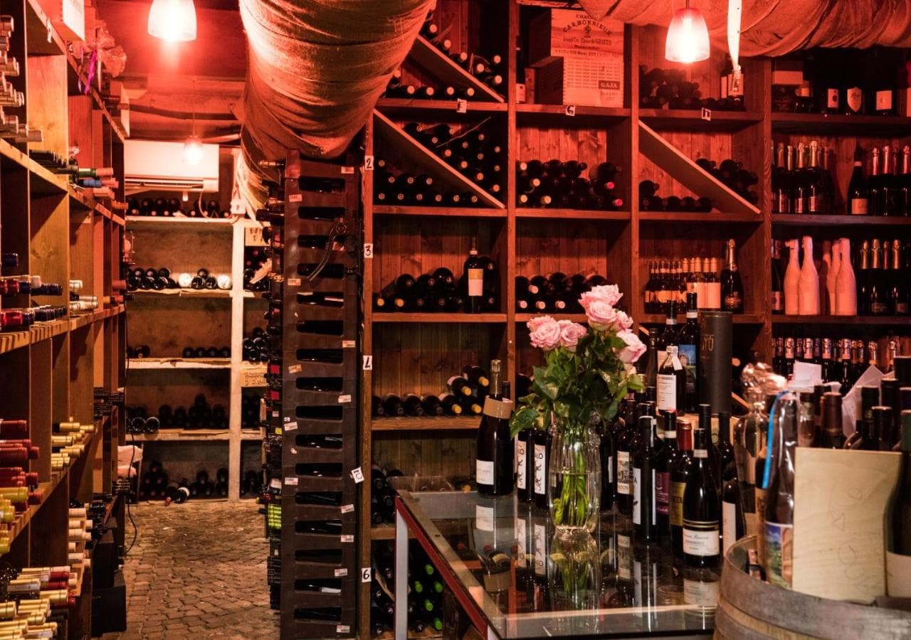 A wine cellar with floor-to-ceiling wooden racks filled with bottles and illuminated by warm lights.