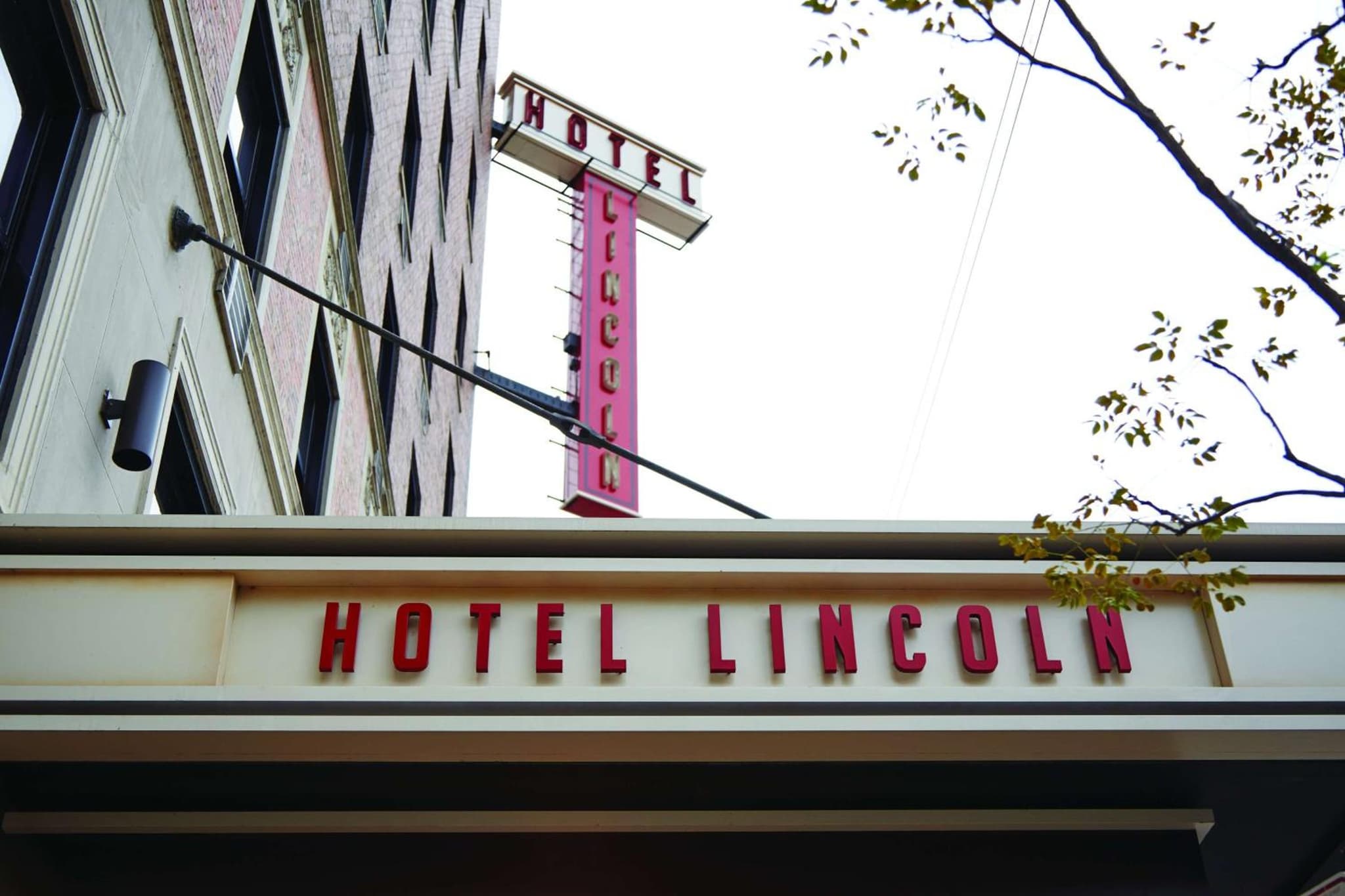 Low-angle view of a vintage vertical sign and entrance marquee against a daytime sky.