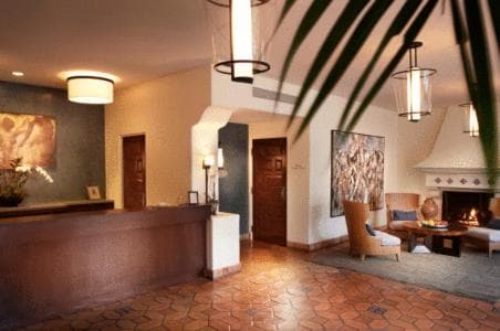A lobby with terracotta tile flooring, a wooden reception counter, and a fireside seating area.