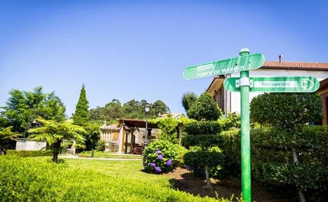 Green directional signpost pointing toward reception, surrounded by flowering hydrangeas and garden greenery.