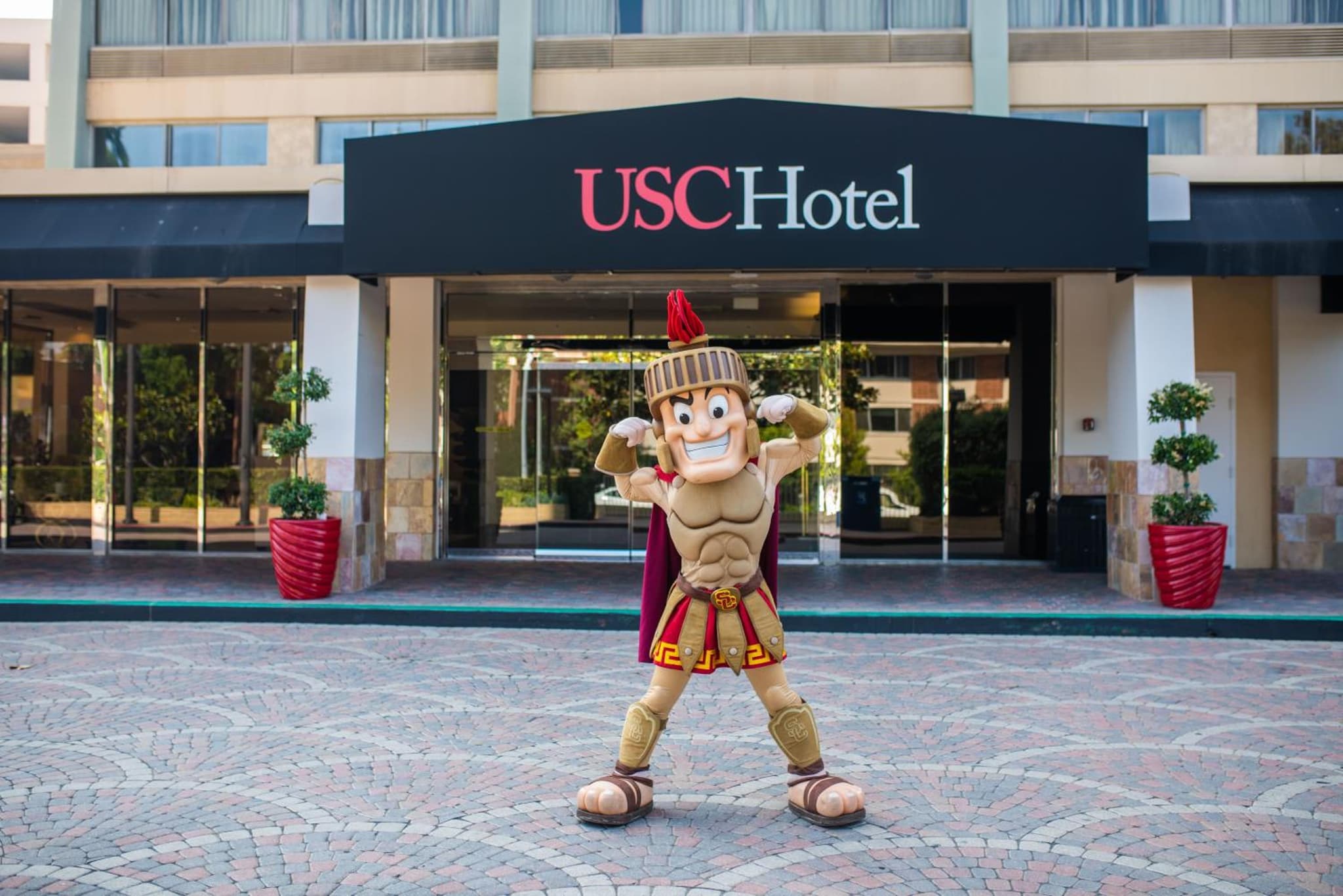 The USC Trojan mascot in full armor costume posing in front of the hotel entrance.