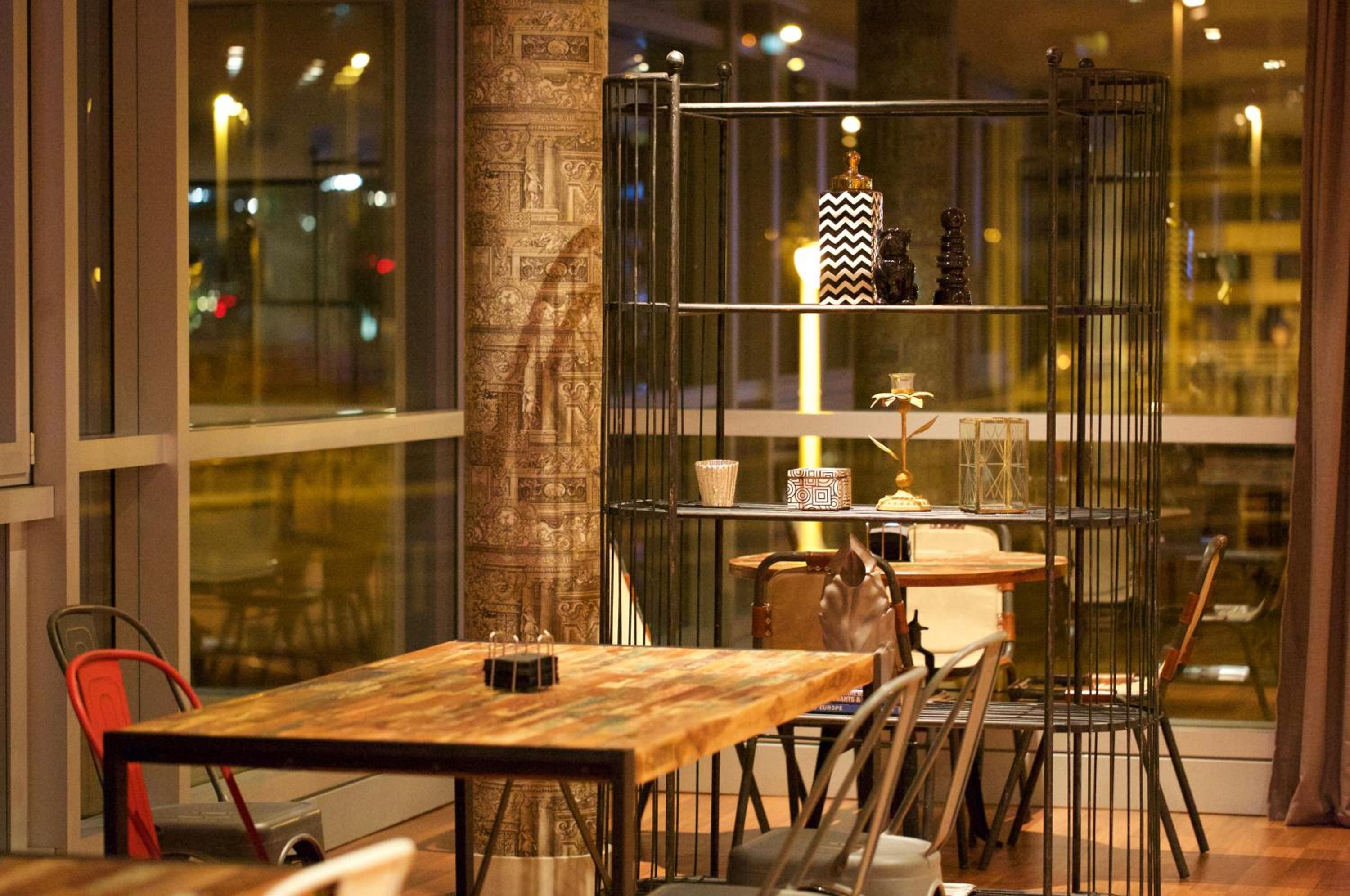 A dining area with a rustic wooden table, metal chairs, and a metal shelving unit with decorative pieces.