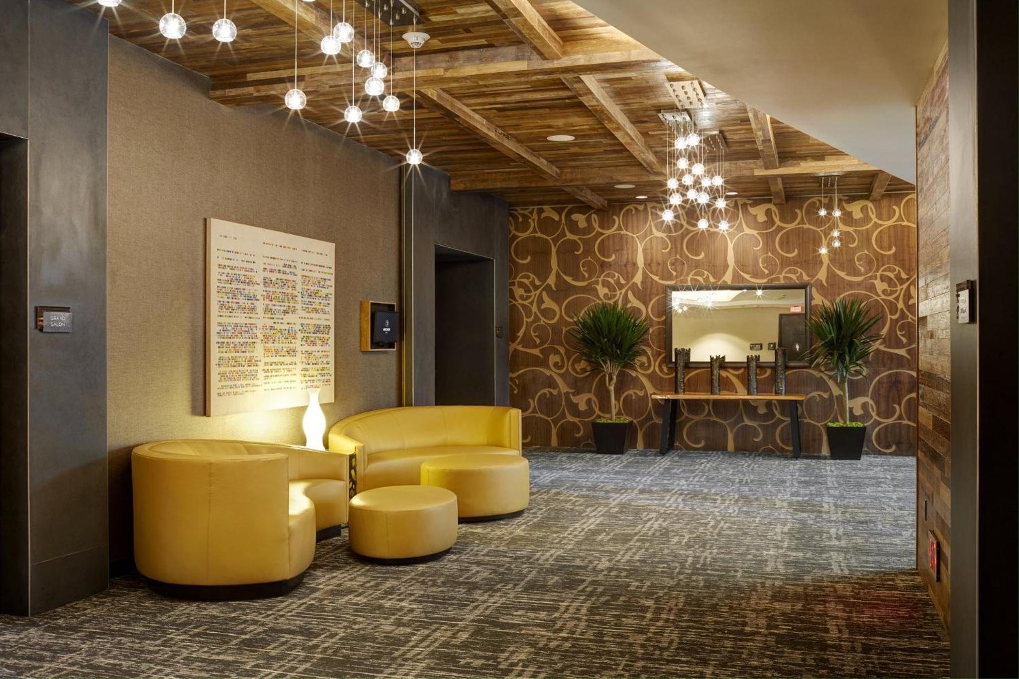 Lounge area featuring yellow seating, patterned carpet, hanging globe lights, and an exposed wood-beamed ceiling.
