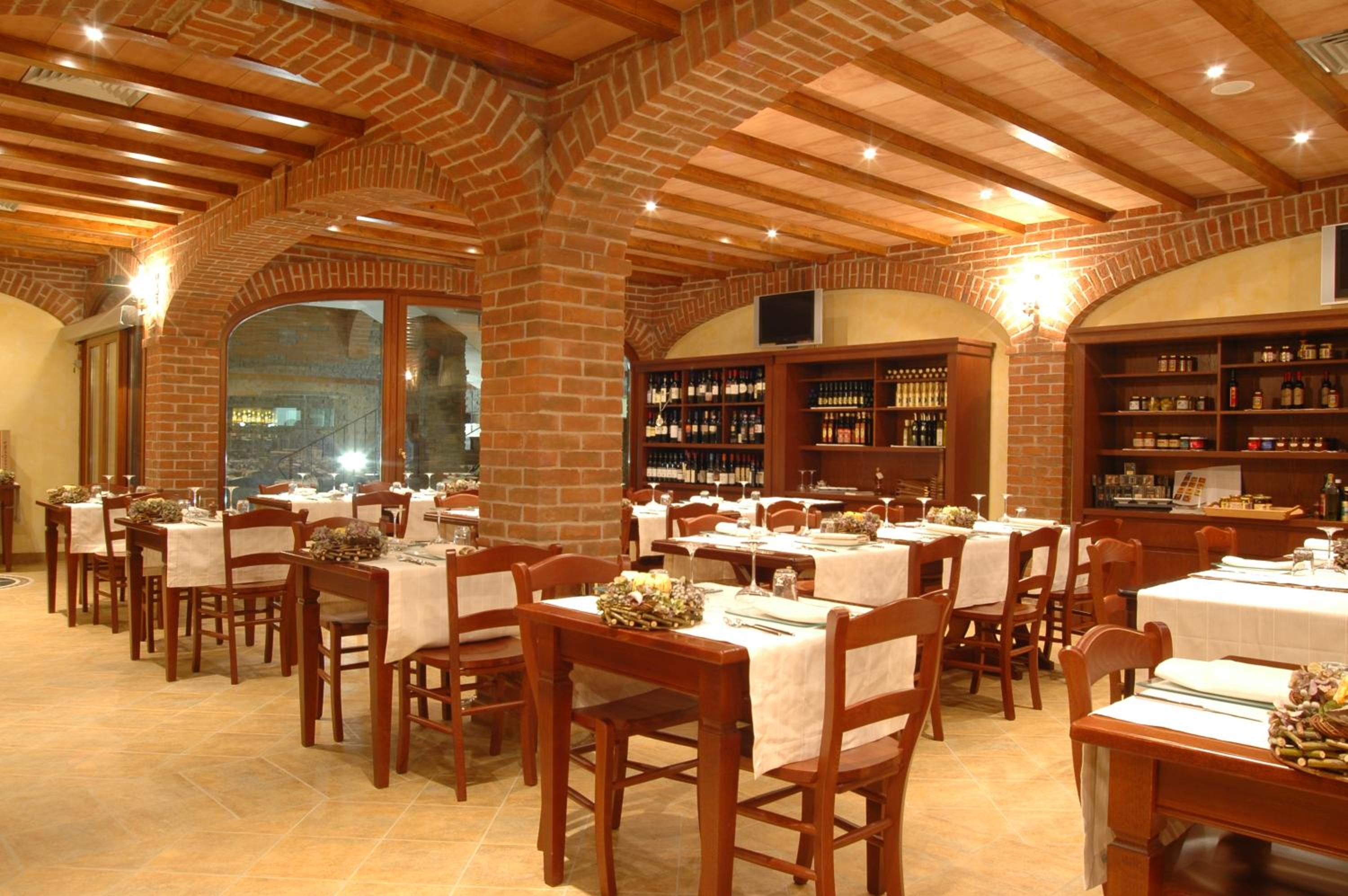 Exposed brick arches and timber ceiling beams cover a restaurant dining room with set wooden tables.