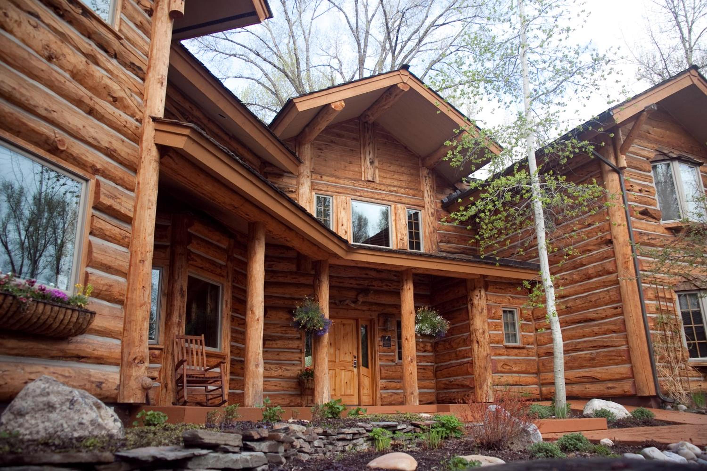 Timber log exterior of Bentwood Inn featuring a covered front porch, wooden pillars, and garden landscaping.