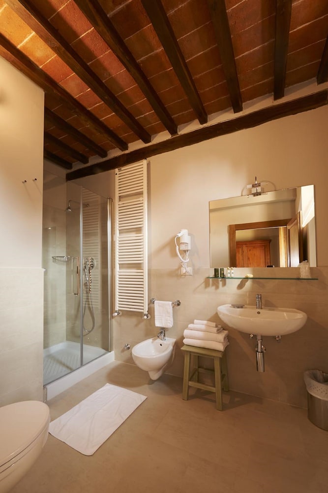 A bathroom with exposed beams and terracotta ceiling, a glass shower stall, sink, and bidet.