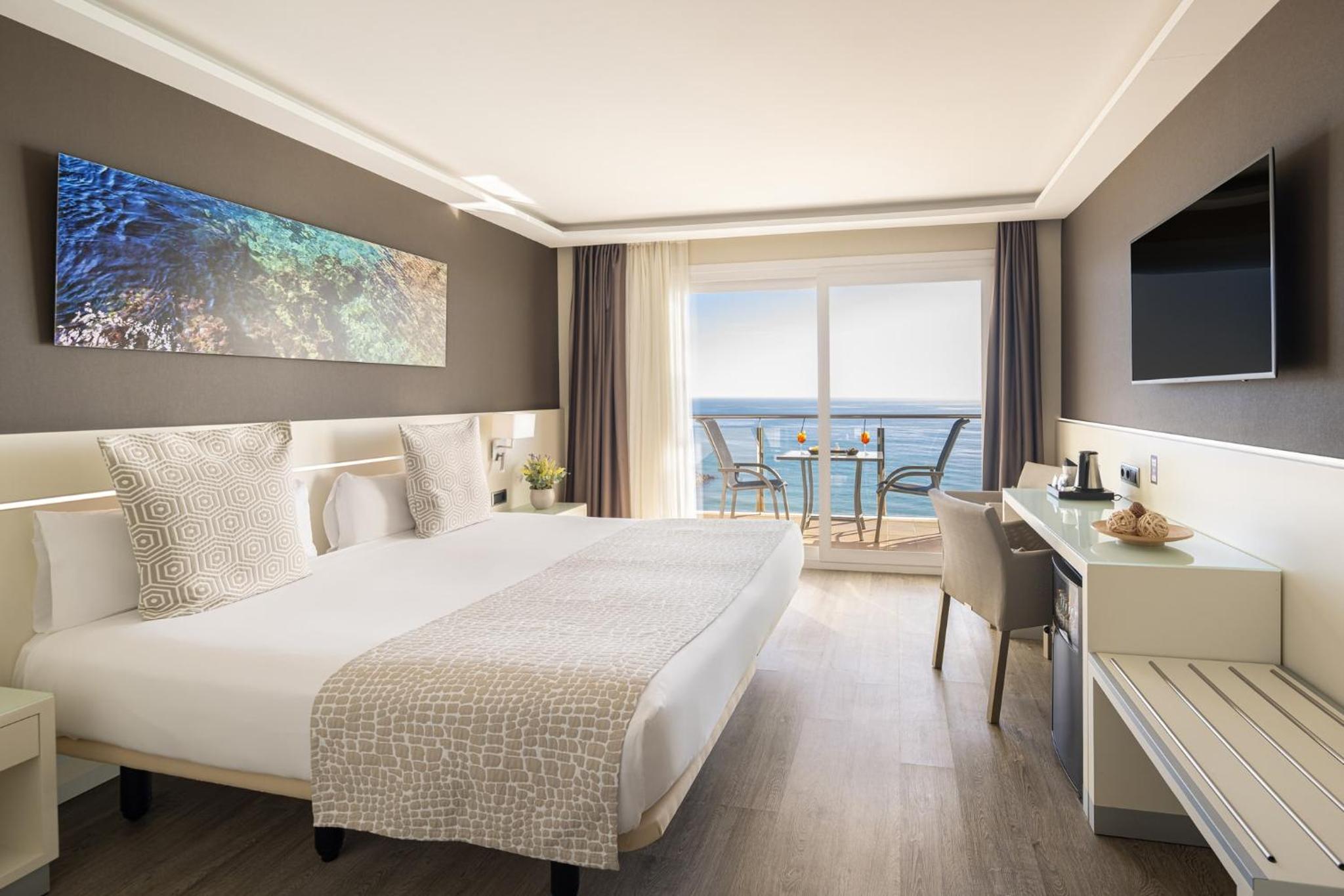 Bedroom with wood flooring, desk, and sliding glass doors opening to a balcony with sea views.