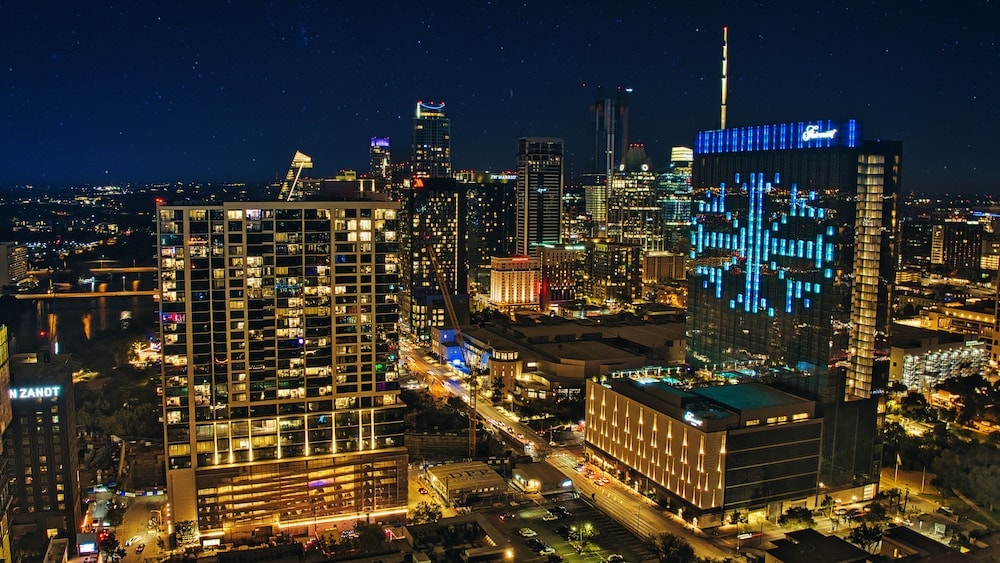 Downtown Austin illuminated at night, viewed from above with glowing skyscrapers under a dark sky.