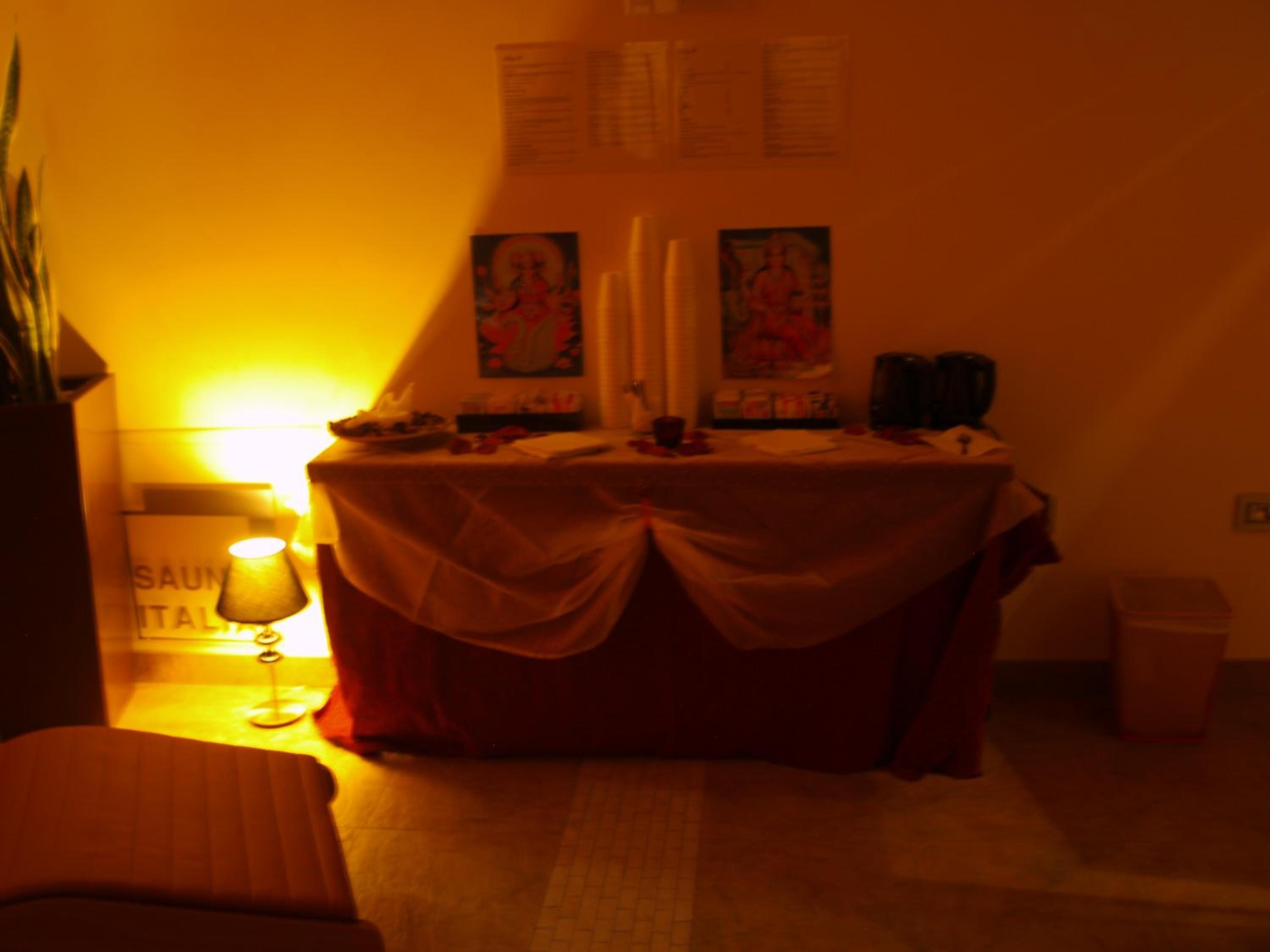 Draped table illuminated by a warm lamp, set against an indoor wall with framed artwork.