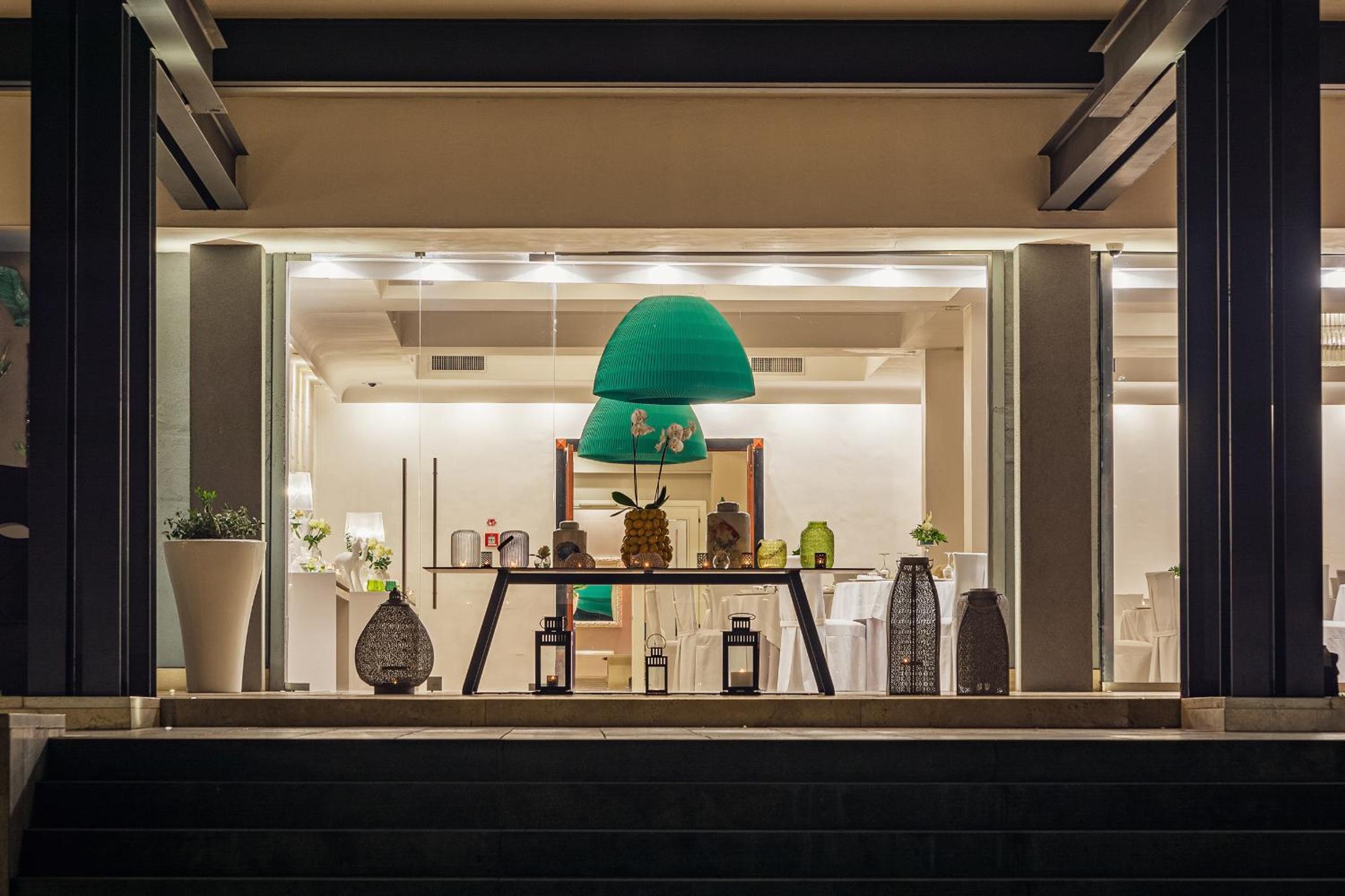 Looking up steps through large glass doors to an interior decorated with lanterns and hanging green pendant lights.