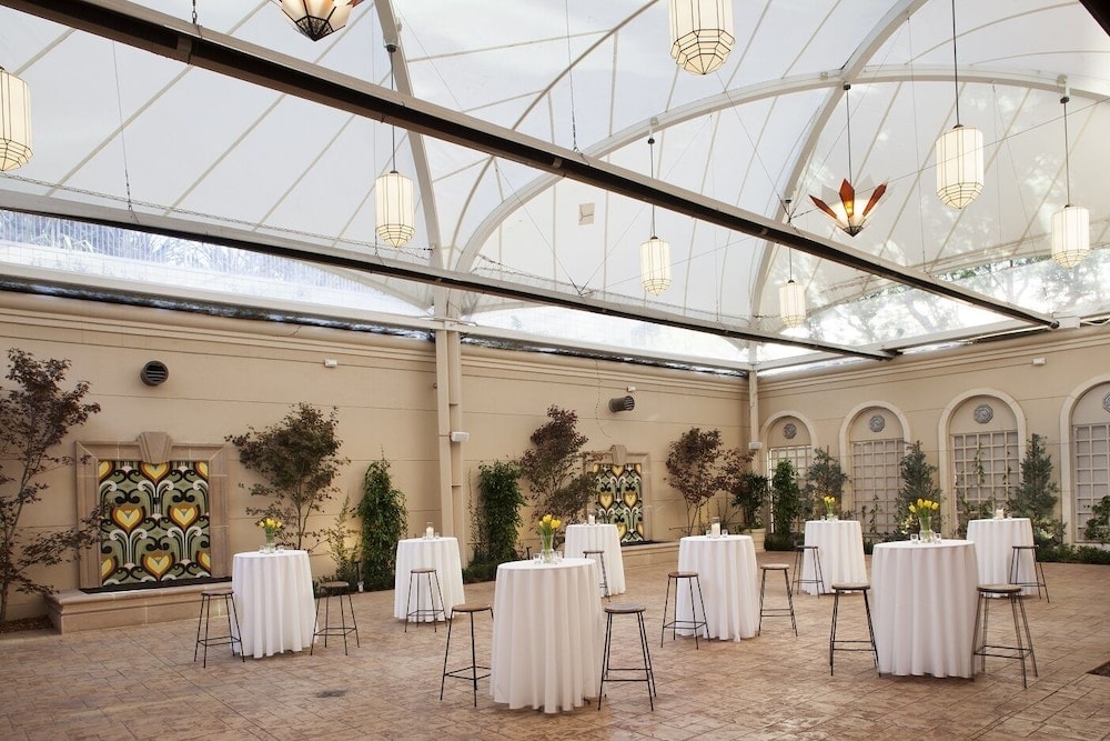 An enclosed courtyard with an arched canopy ceiling, hanging lanterns, and cocktail tables dressed in white linens.