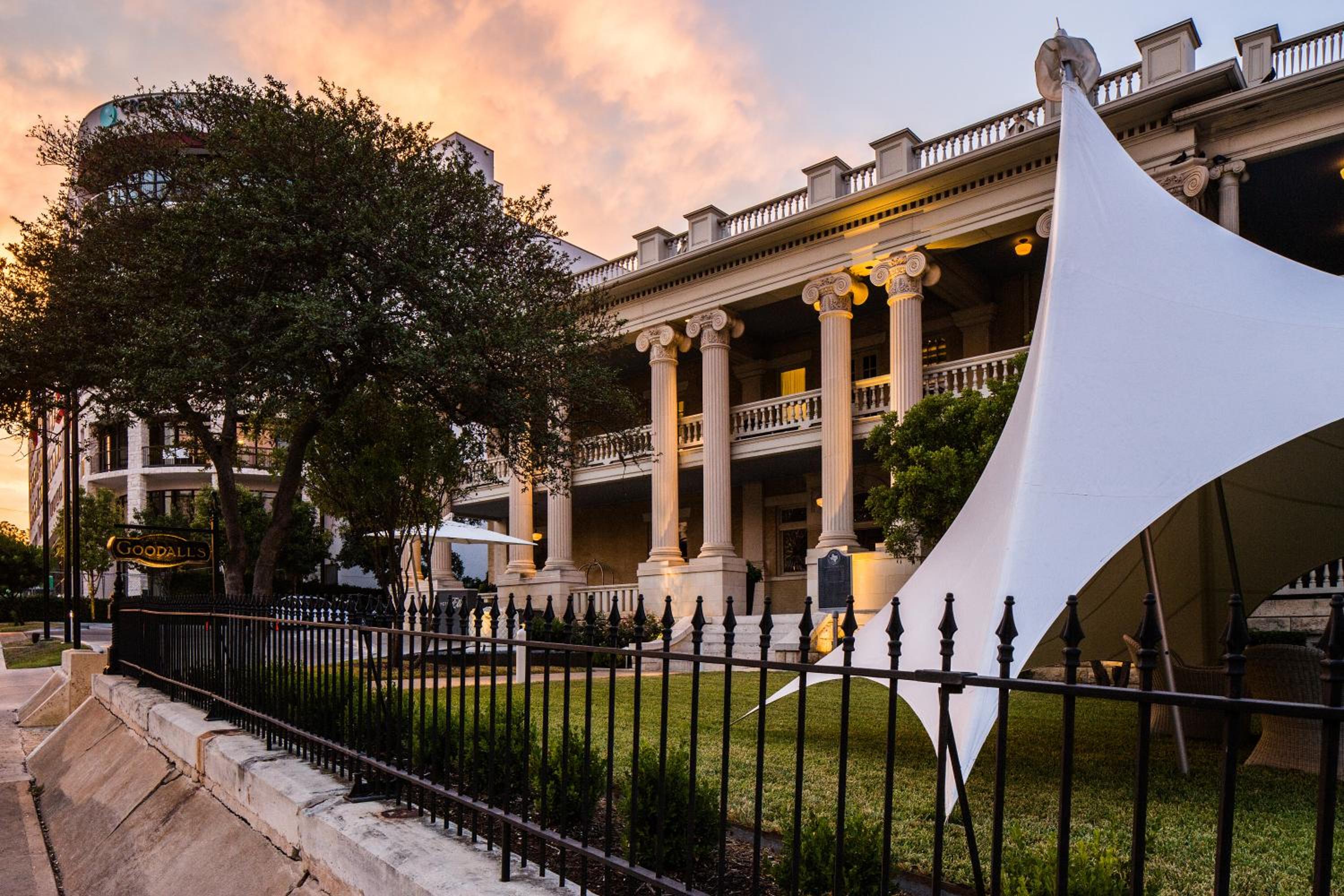 White canopy tent on the lawn outside the columned mansion exterior at sunset.