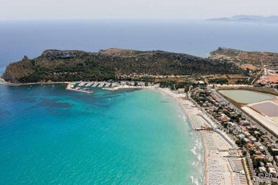Aerial view of a turquoise bay and sandy beach curving along a rocky coastal headland.