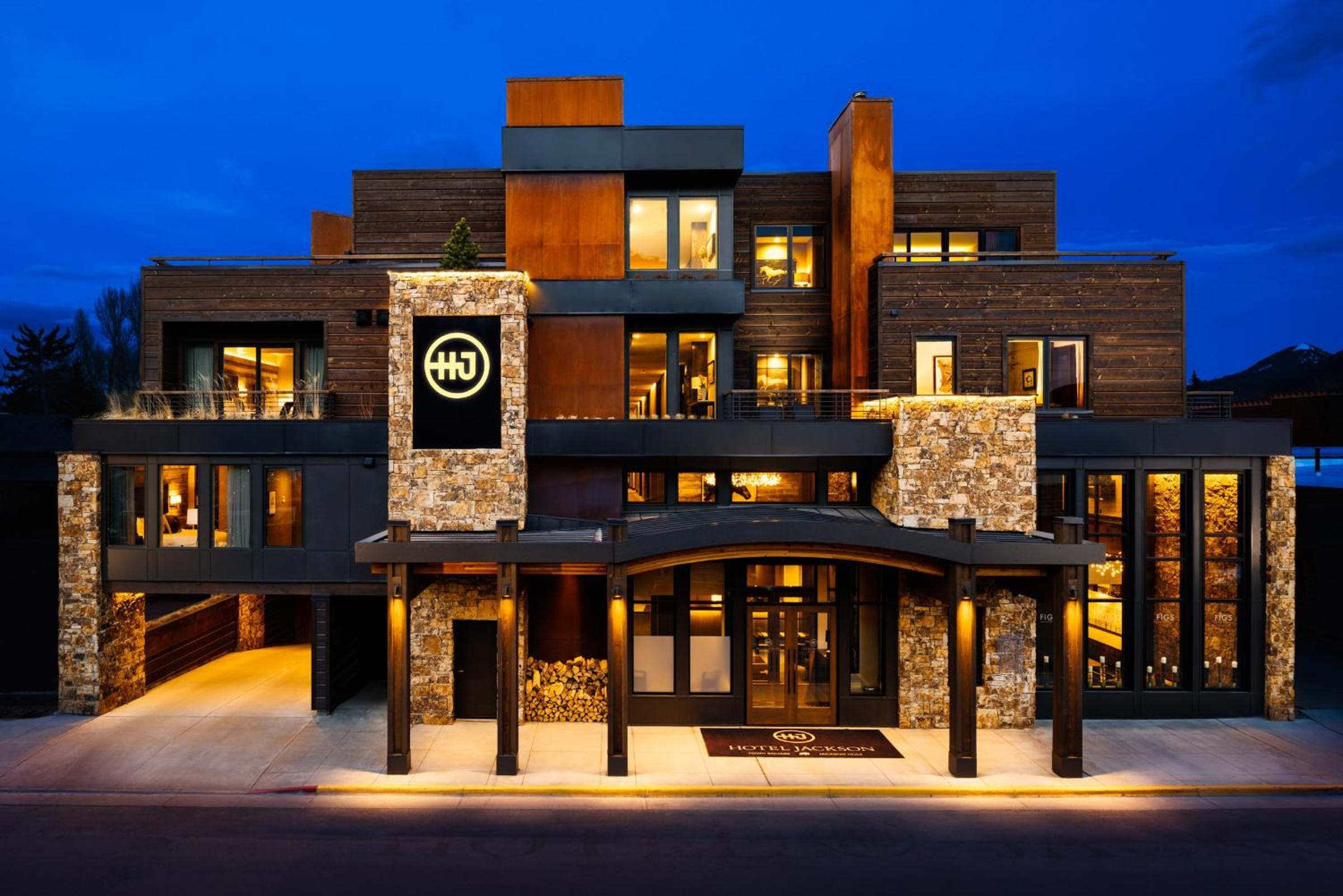 The exterior facade of Hotel Jackson at dusk, built from dark wood, rusted metal, and stone.