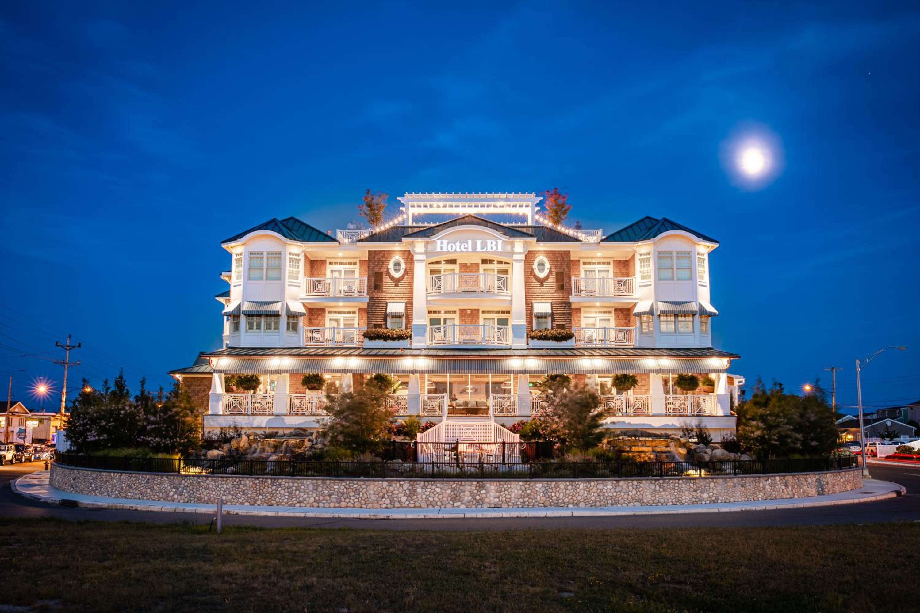 Illuminated facade of Hotel LBI at dusk under a deep blue sky with the moon visible above.
