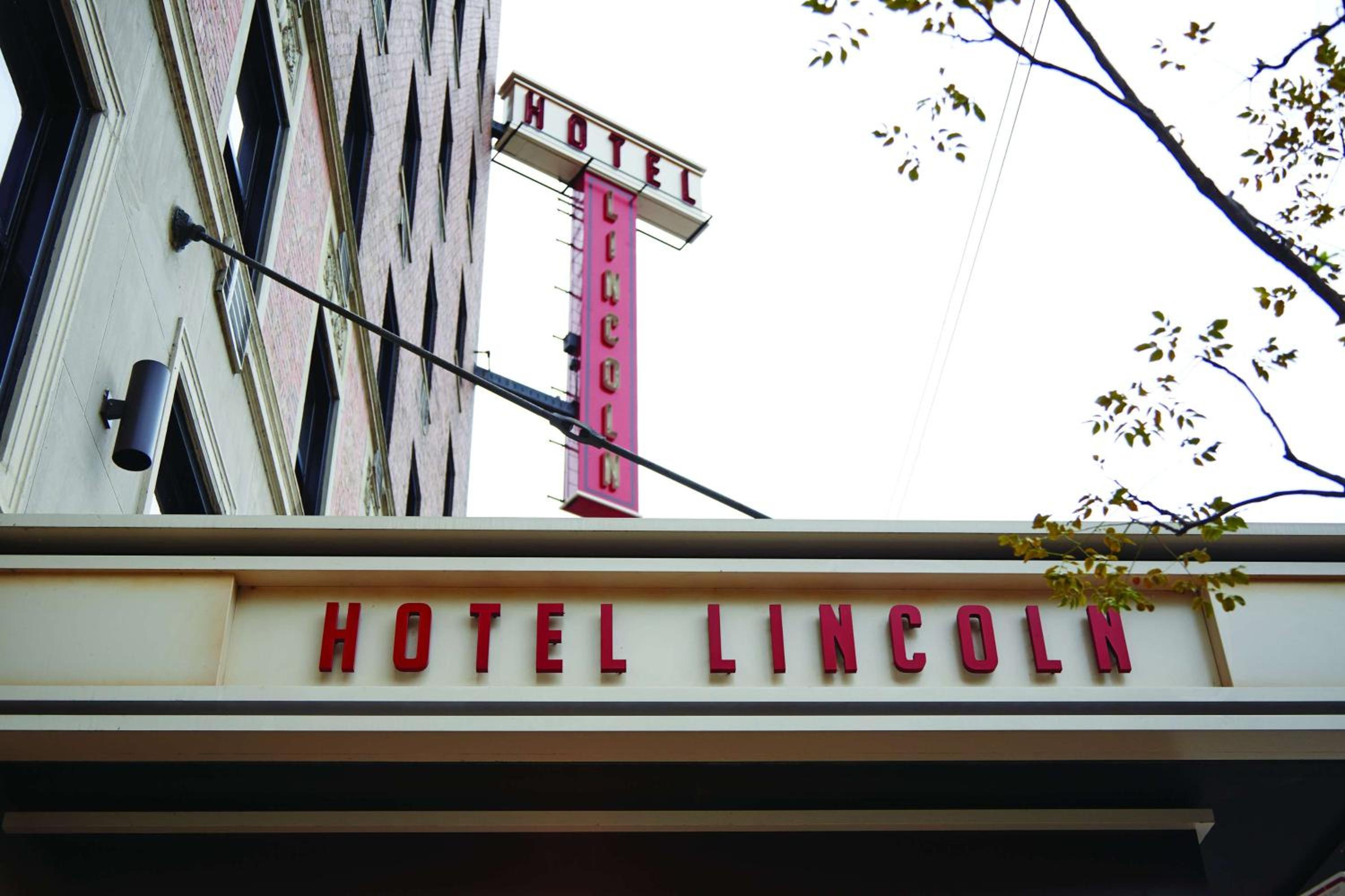 Low-angle view of a vintage vertical sign and entrance marquee against a daytime sky.