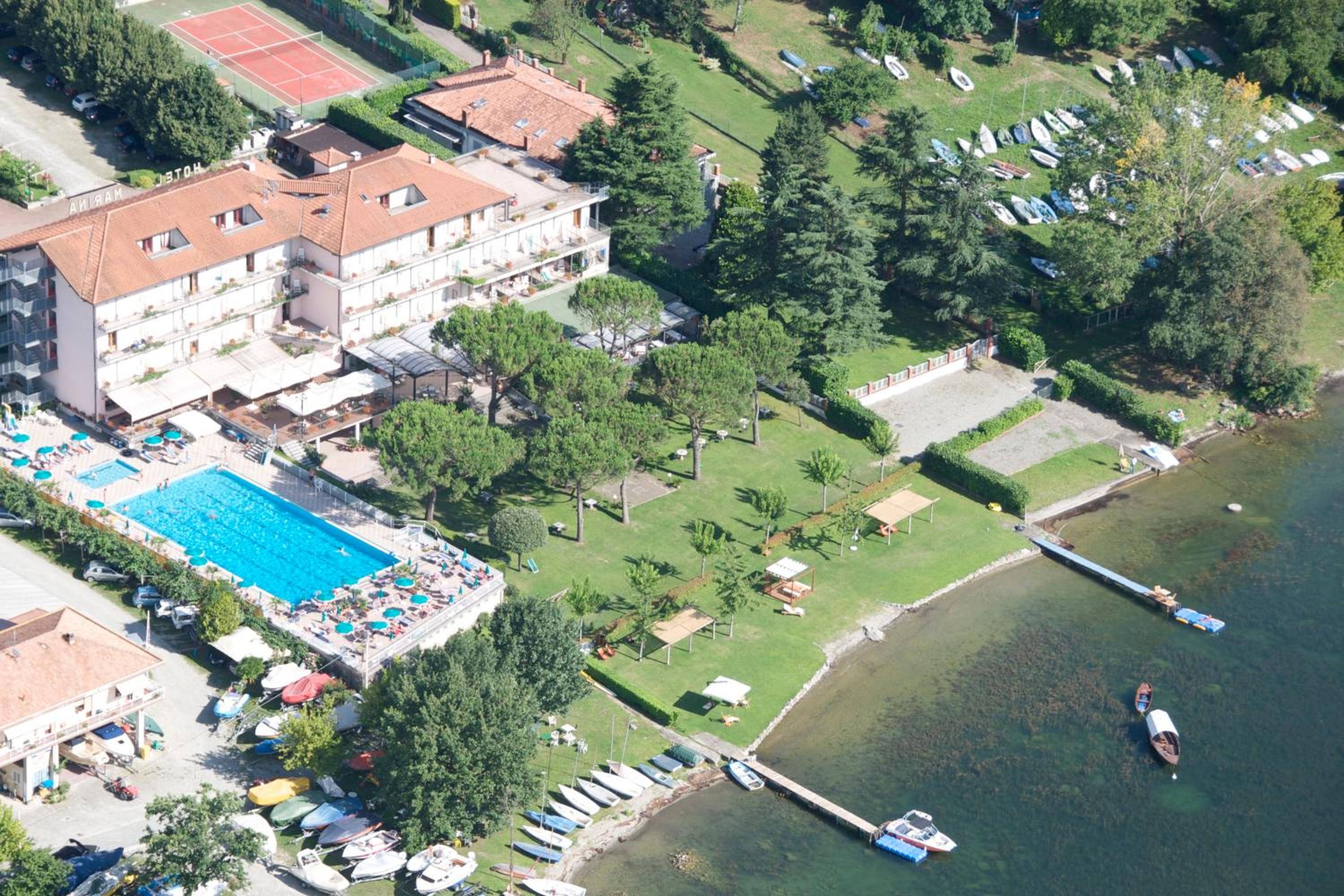 Aerial view of lakeside hotel grounds with a swimming pool, lawn, and piers on the water.