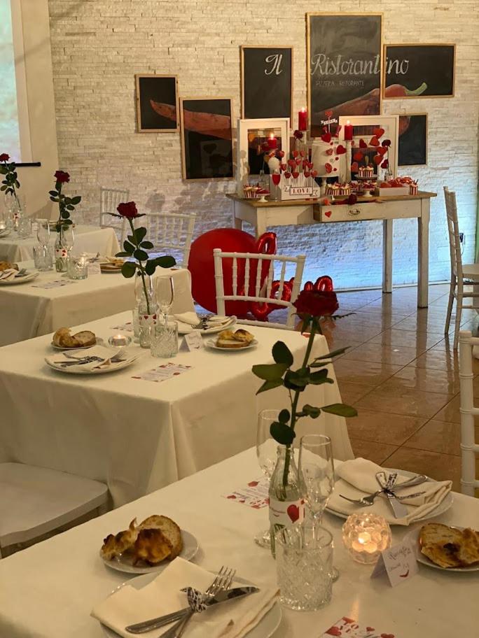 Tables dressed in white with red roses and candles set before a stone wall in the dining area.