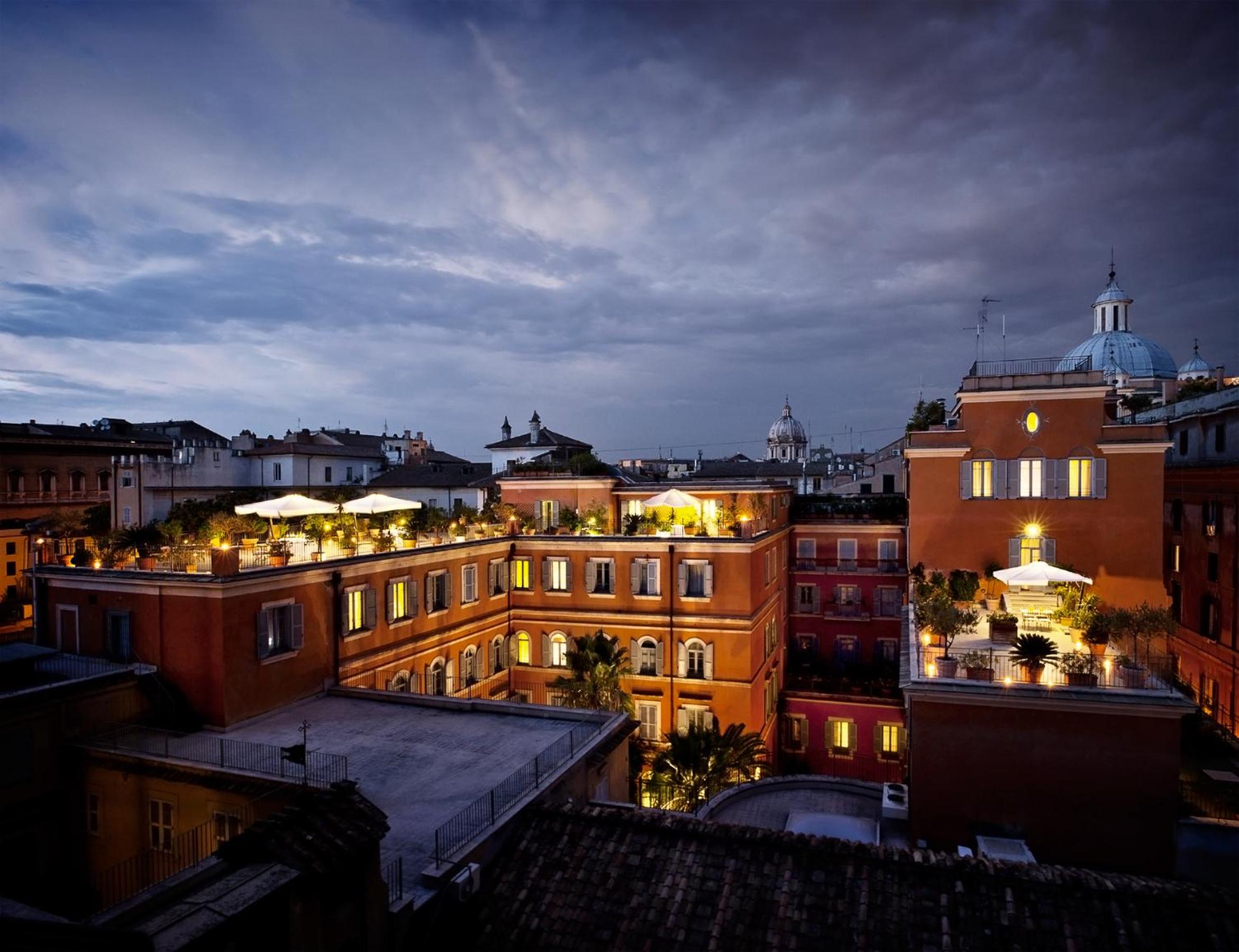 Rooftop terraces lit at dusk overlook an inner courtyard and surrounding city rooftops.