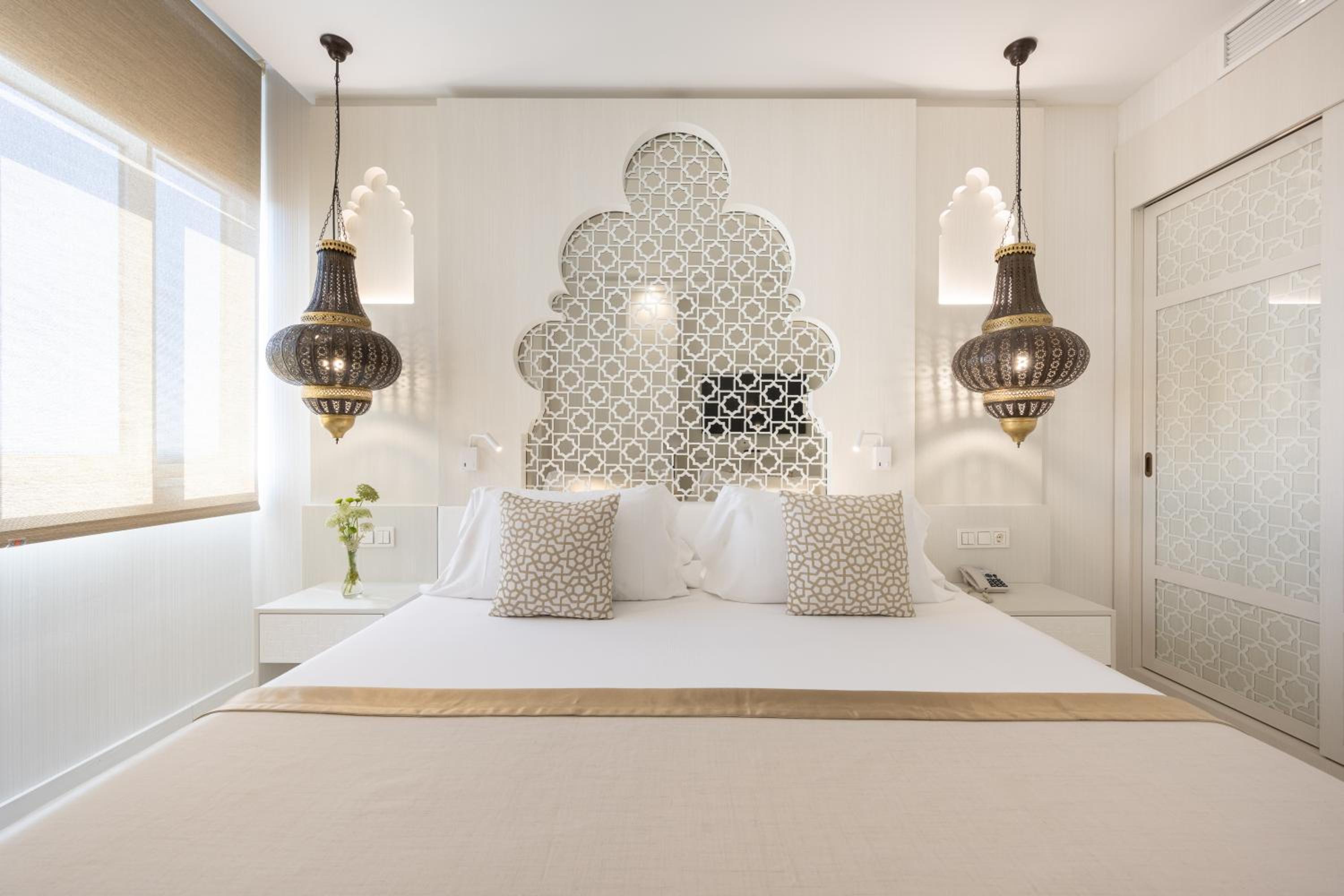 A bedroom at Hotel Saray with intricate lattice headboard detail, pendant lanterns, and nightstands.