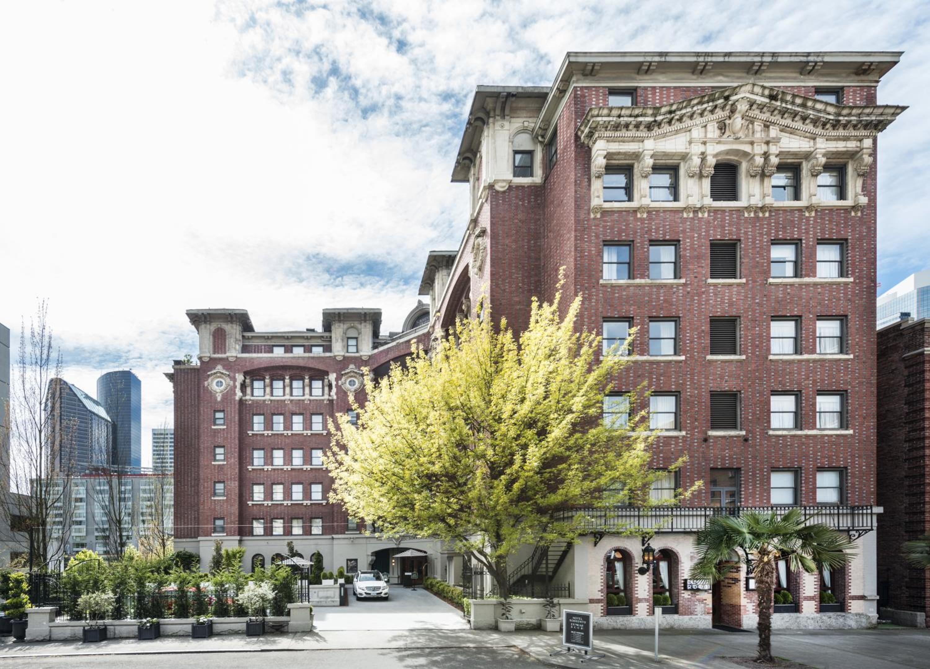 Exterior brick facade of Hotel Sorrento with ornate stonework cornices, front driveway, and trees.