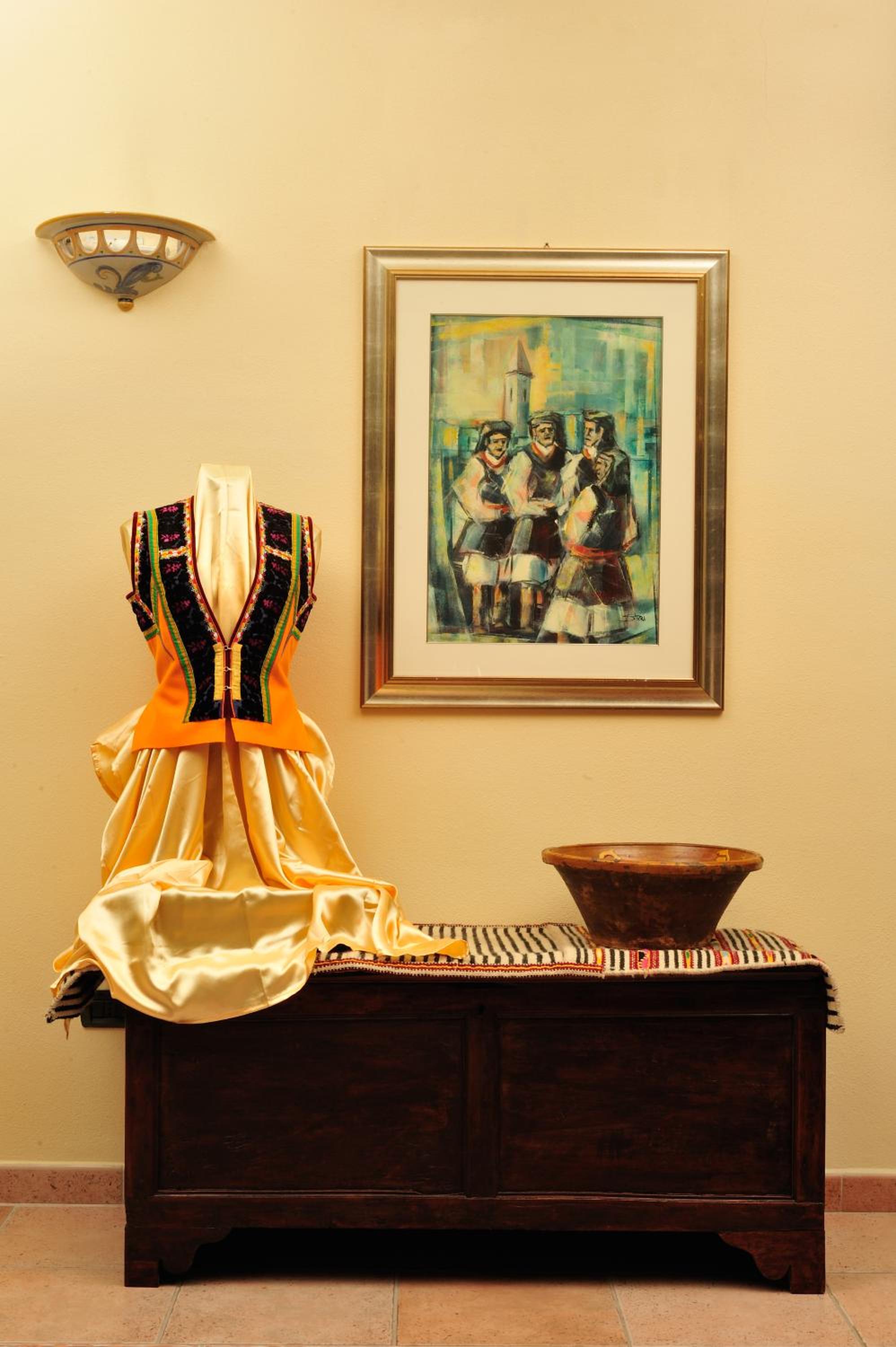 Traditional embroidered folk costume displayed on a wooden chest beneath a framed painting.