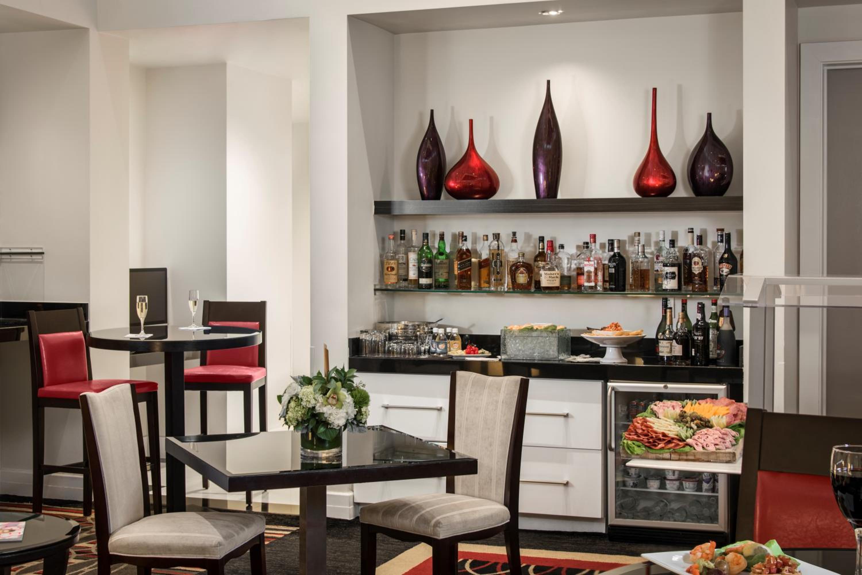 A lounge area with a liquor shelf, snack bar, polished dark tables, and decorative vases.