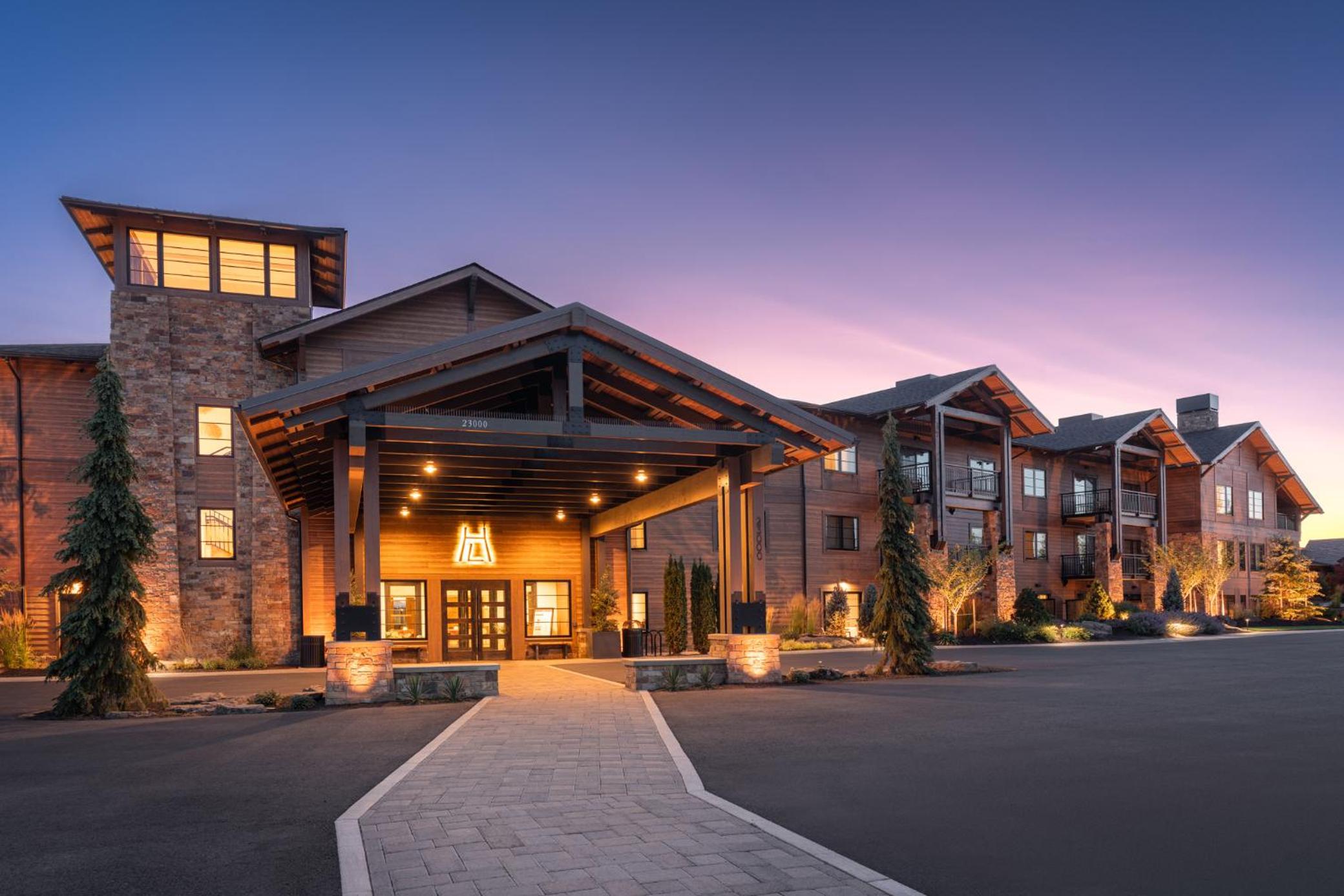 Wood and stone lodge entrance of Juniper Preserve under a twilight sky with an illuminated portico.