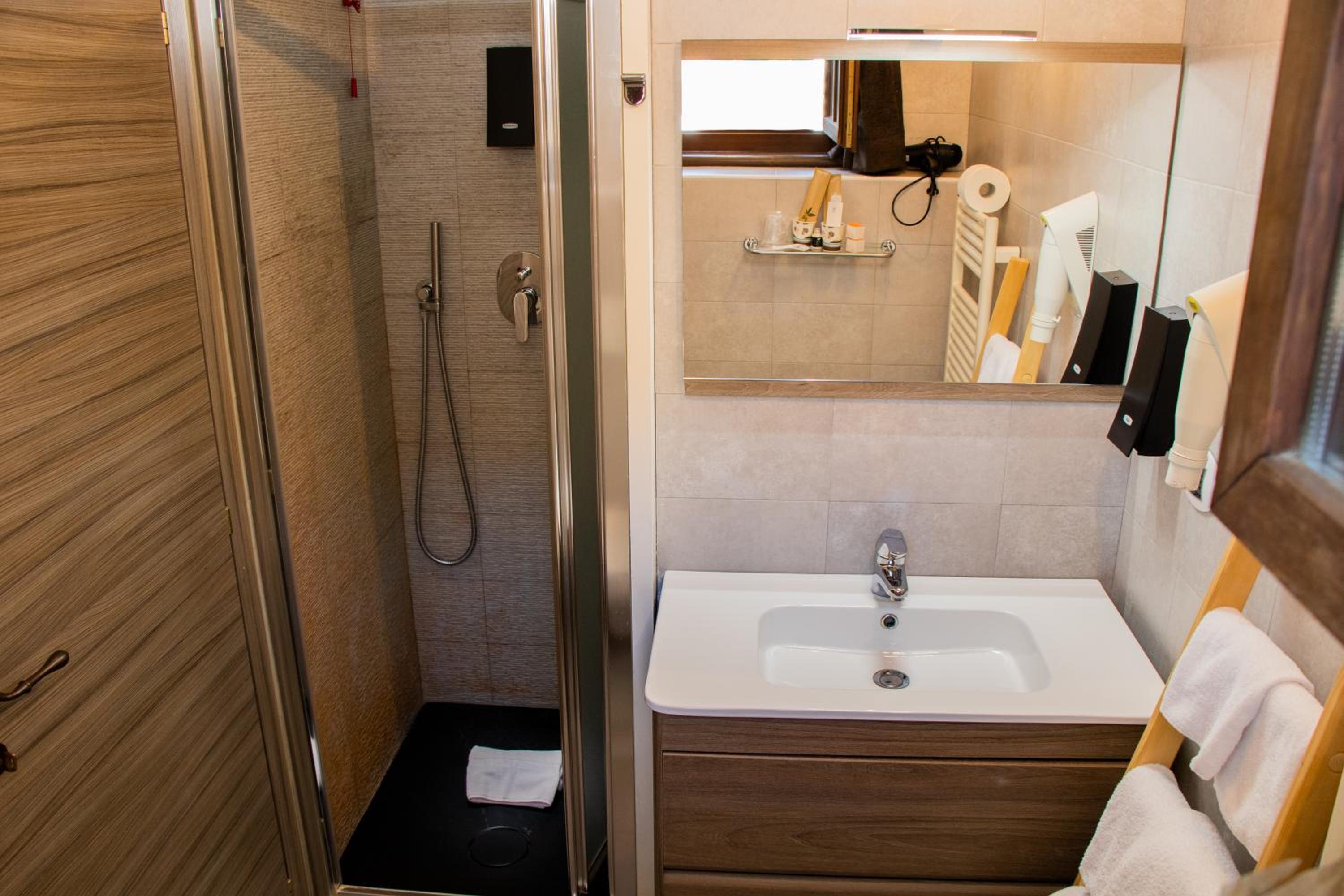 A modern bathroom with a wooden vanity, rectangular mirror, and glass shower enclosure.