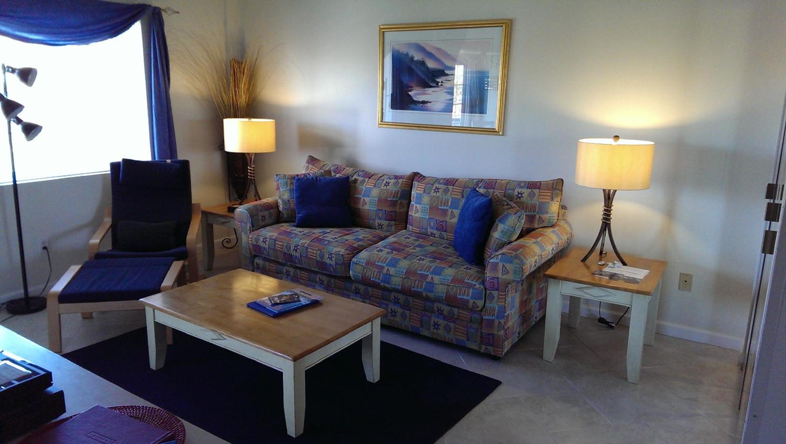 Living room with patterned sofa, wooden coffee table, armchair, and lamps on side tables.