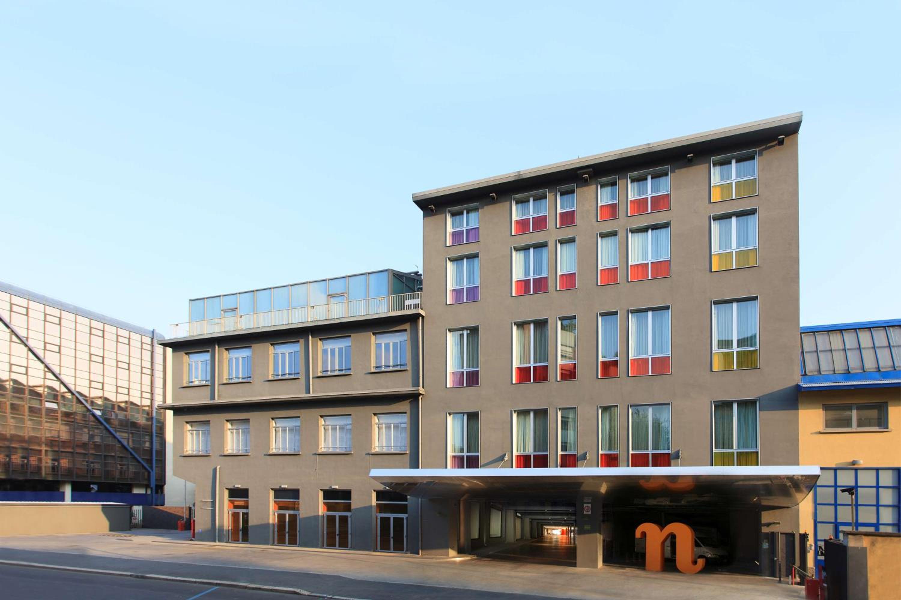 The exterior facade of Nhow Milano with colored window insets and a covered driveway entrance.