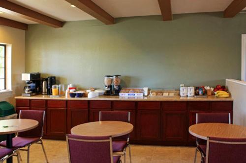 A dining area with round tables, chairs, and a long wooden buffet counter beneath an exposed-beam ceiling.