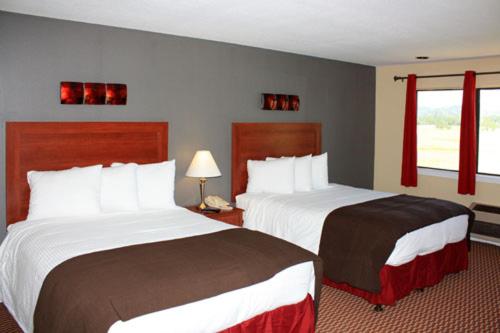 A guest room with wood-headboard beds, red curtains framing a window, and a gray accent wall.