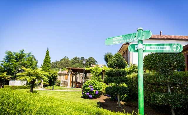 Green directional signpost pointing toward reception, surrounded by flowering hydrangeas and garden greenery.