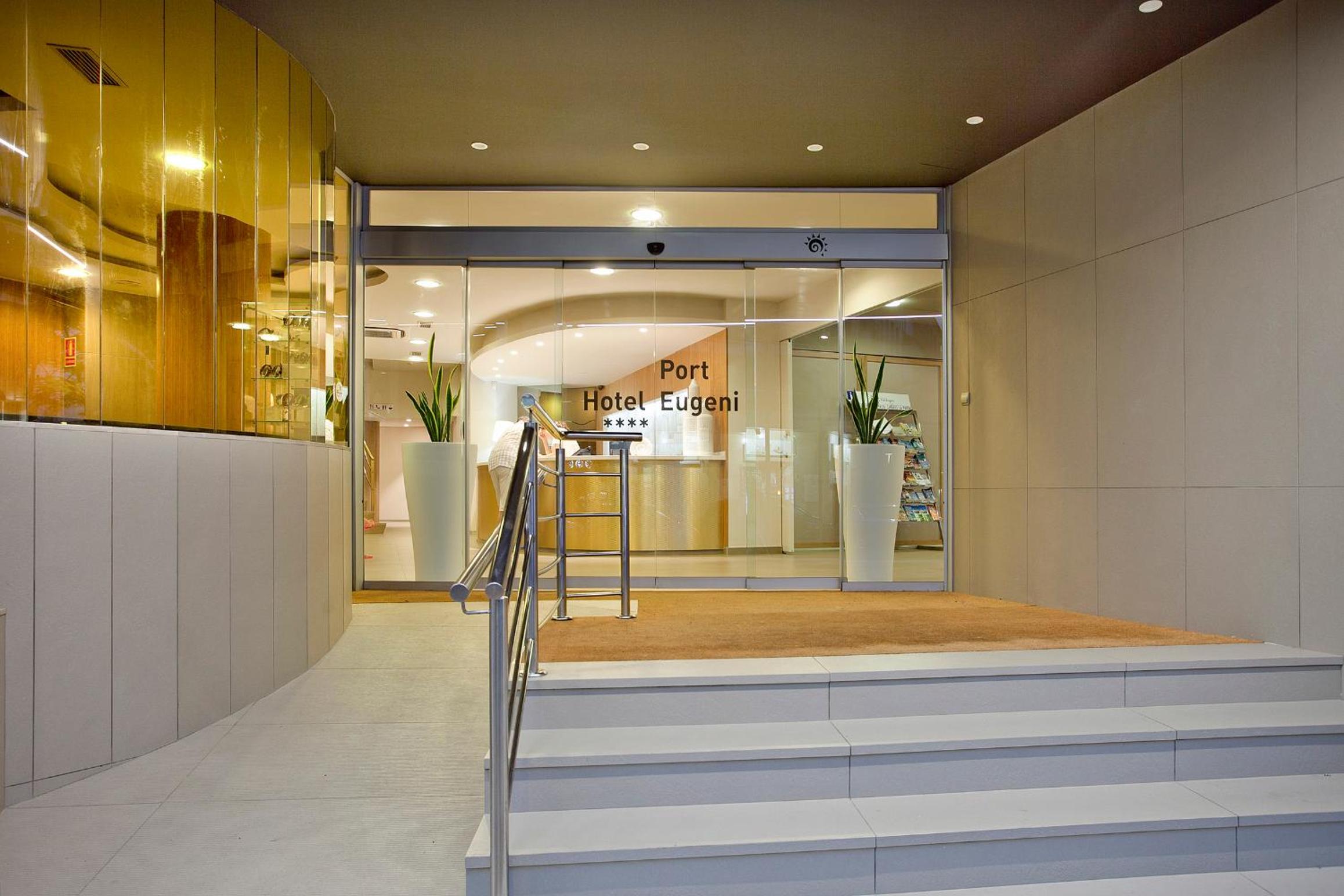 Tiled steps with metal handrails leading to glass sliding entrance doors opening onto a reception area.