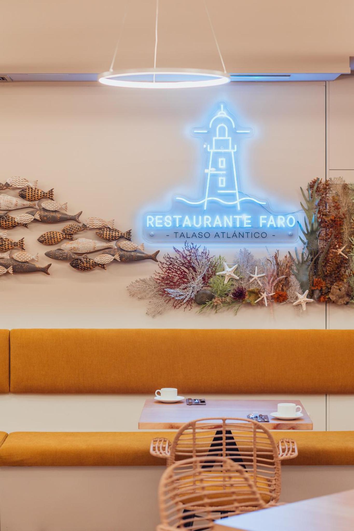 A dining booth beneath a blue neon lighthouse sign decorated with fish carvings and dried sea flora.