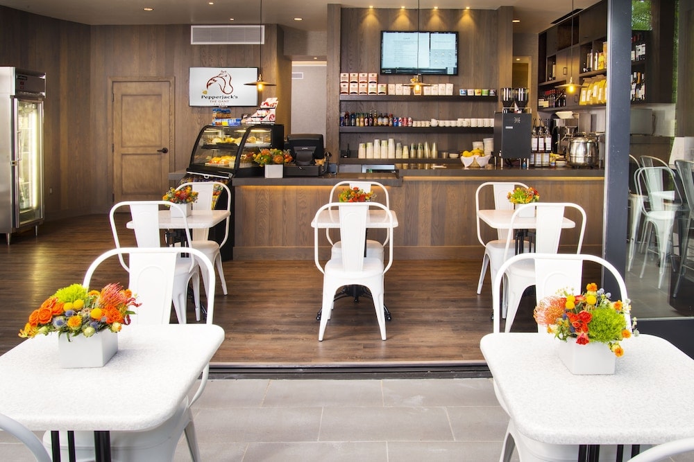 Cafe interior with small tables, white chairs, floral arrangements, and a wood-paneled service counter.