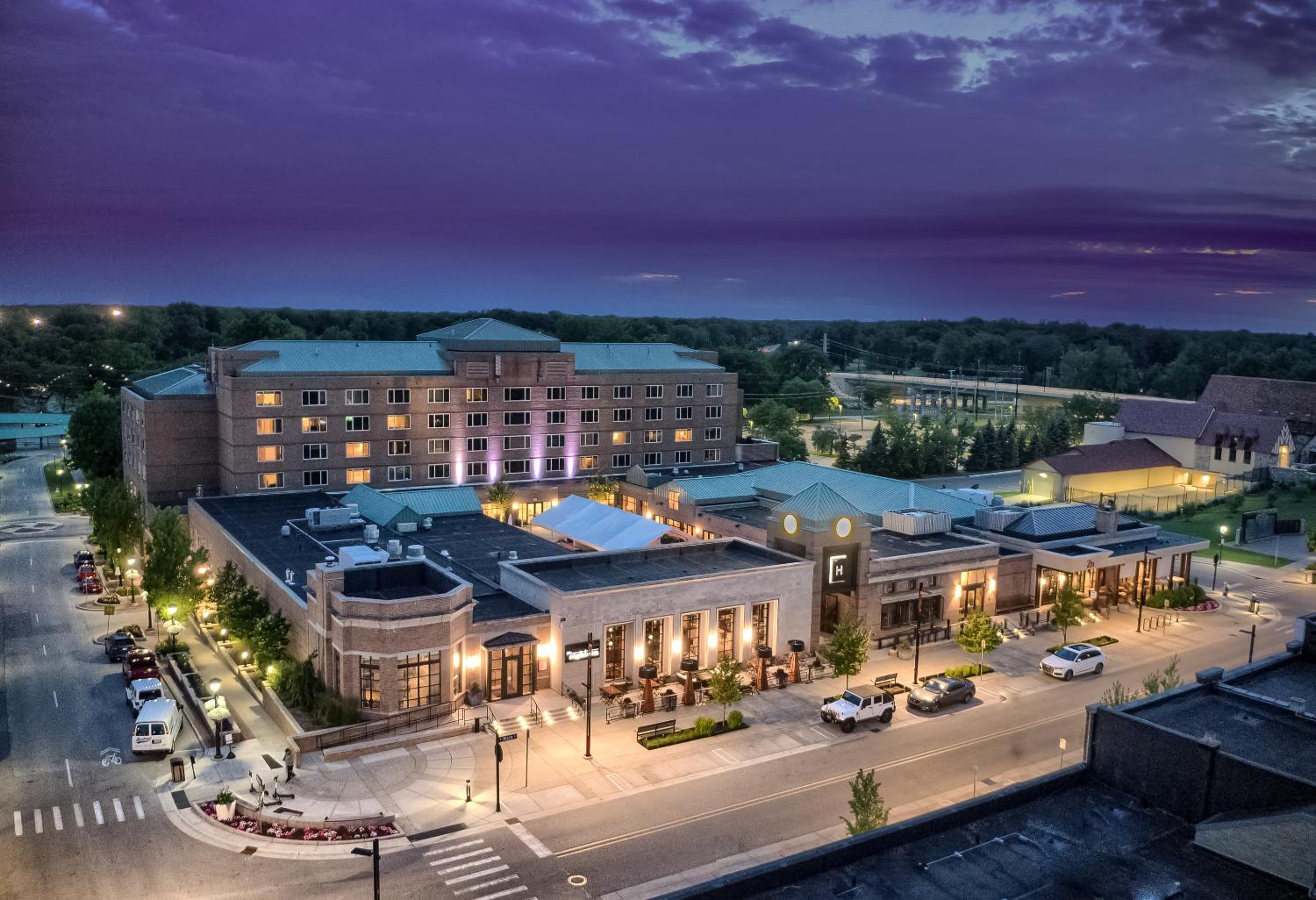 Twilight aerial view of The H Hotel exterior and street level patios glowing with warm light.
