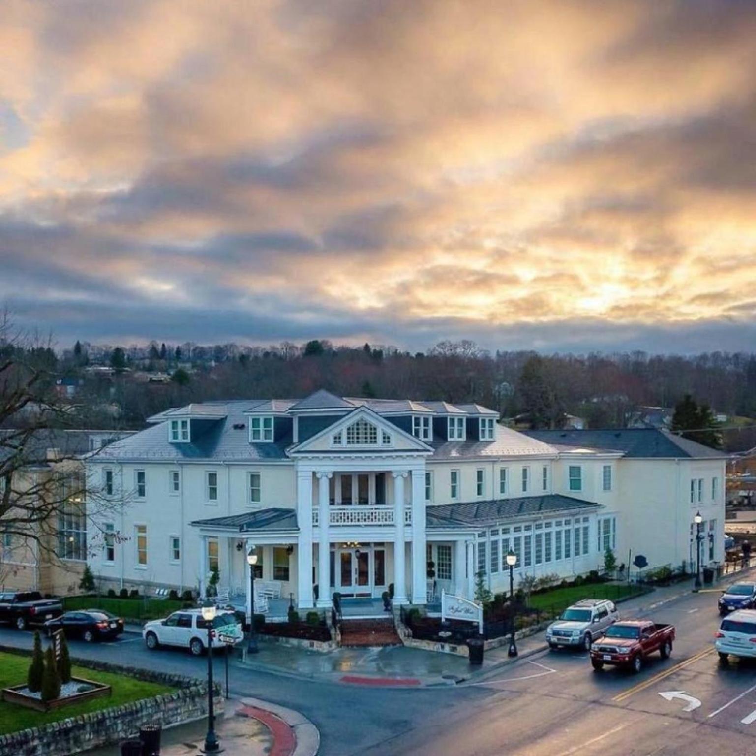 Exterior aerial view of The Inn at Wise featuring white columns and a portico under a cloudy sunset sky.