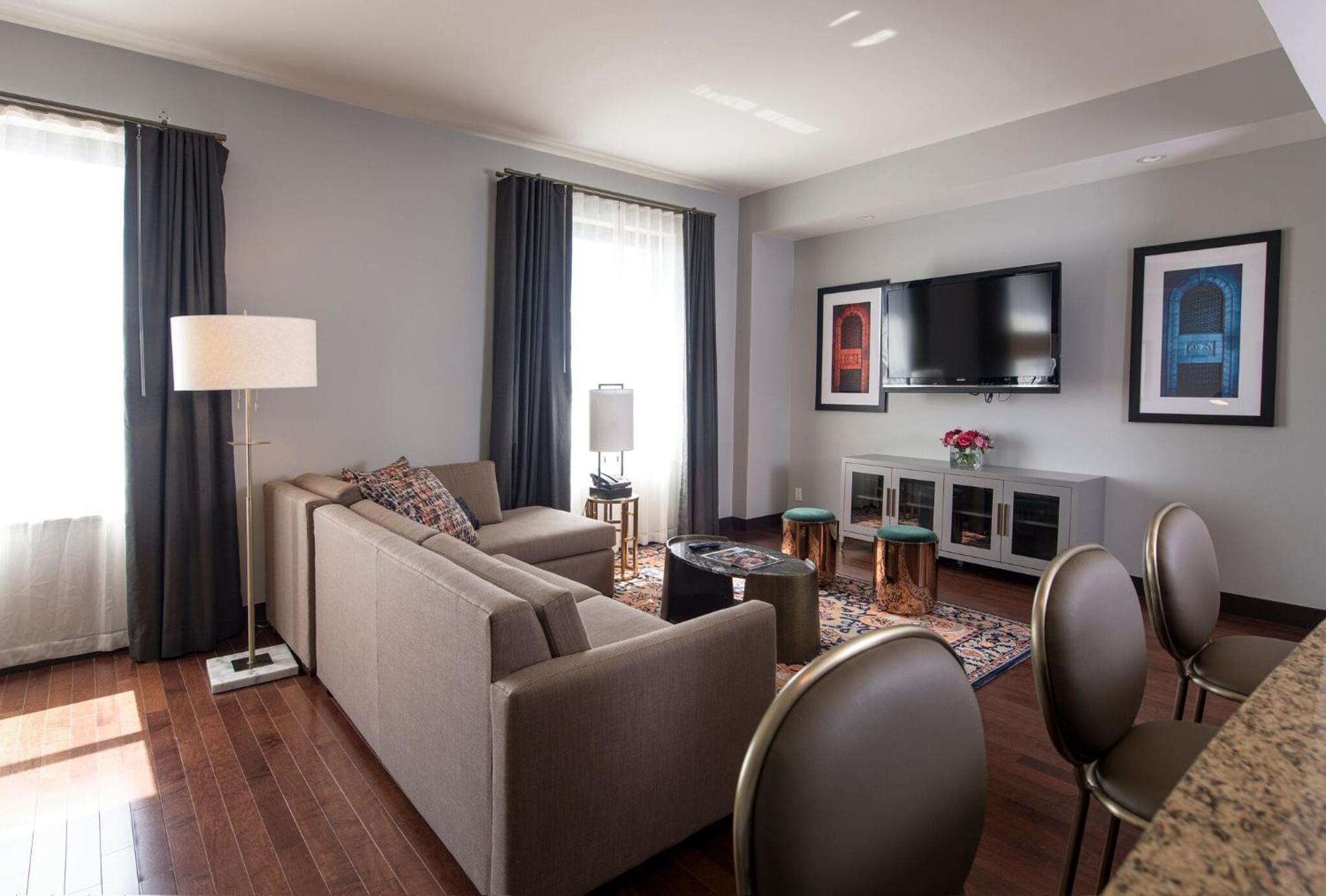 A living area with hardwood floors, a sectional sofa, a coffee table, and a wall-mounted television.