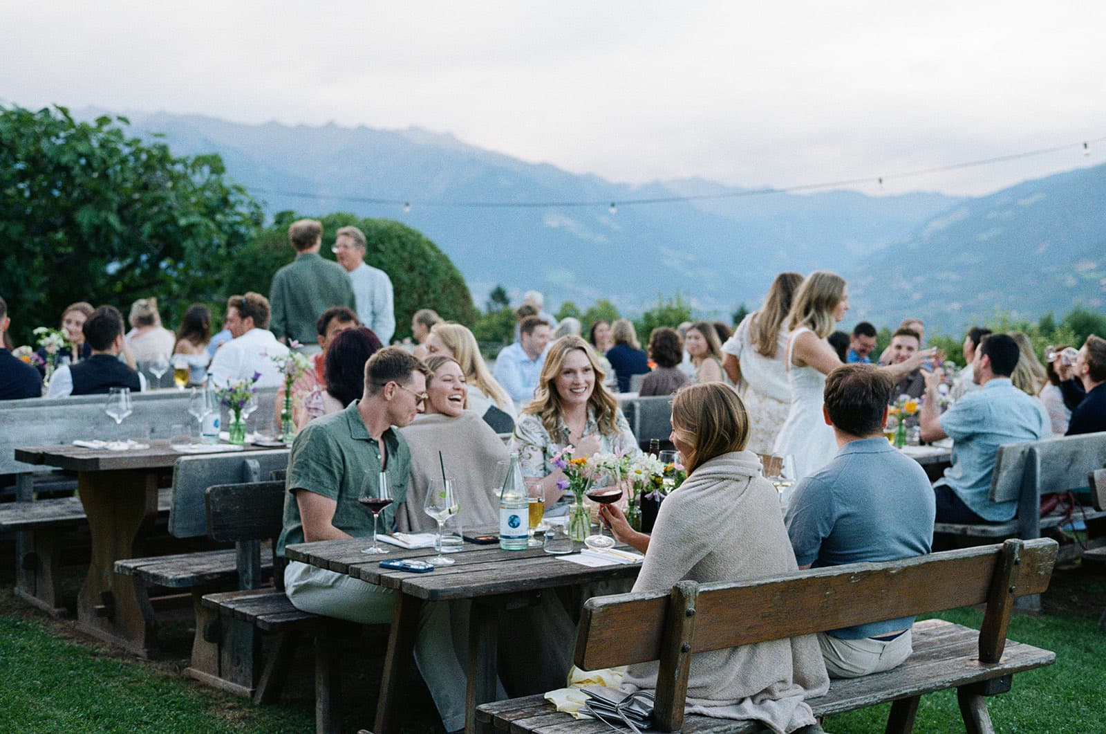 Guests laughing at long wooden tables at the welcome dinner in the hills above Merano