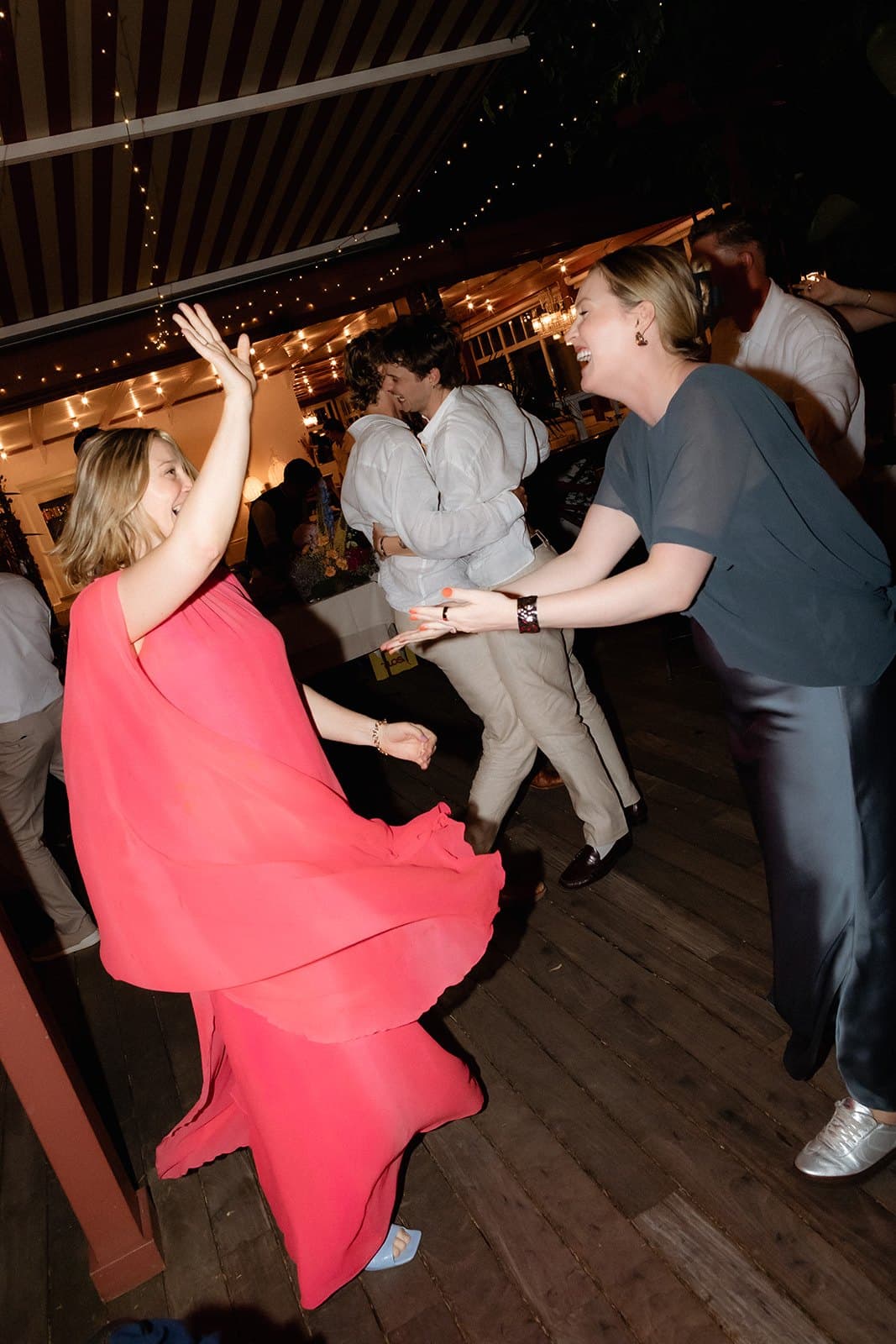 A guest in a pink dress twirling on the dance floor at night