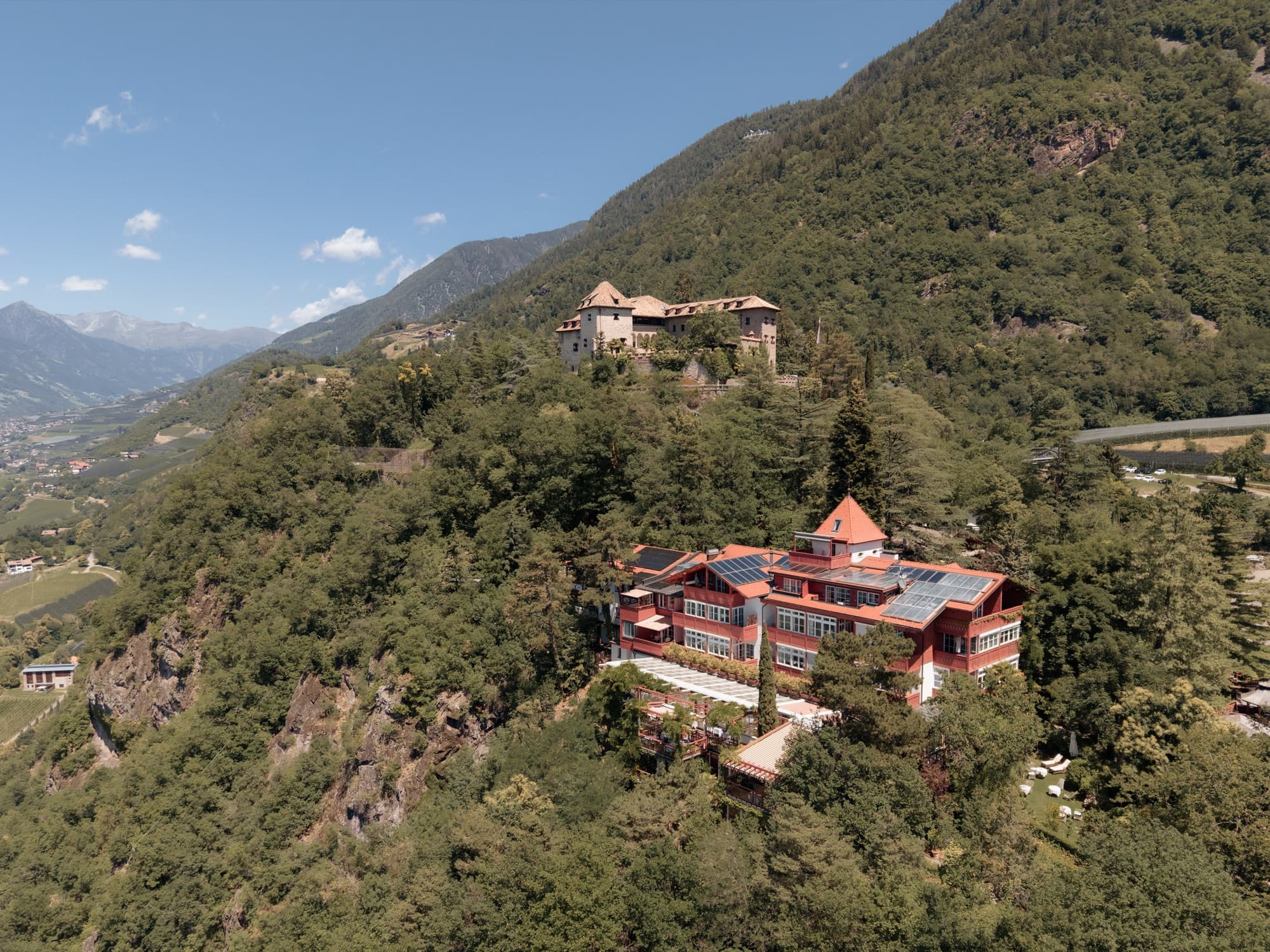 Aerial view of Castel Fragsburg, a castle hotel on a wooded ridge above Merano, South Tyrol