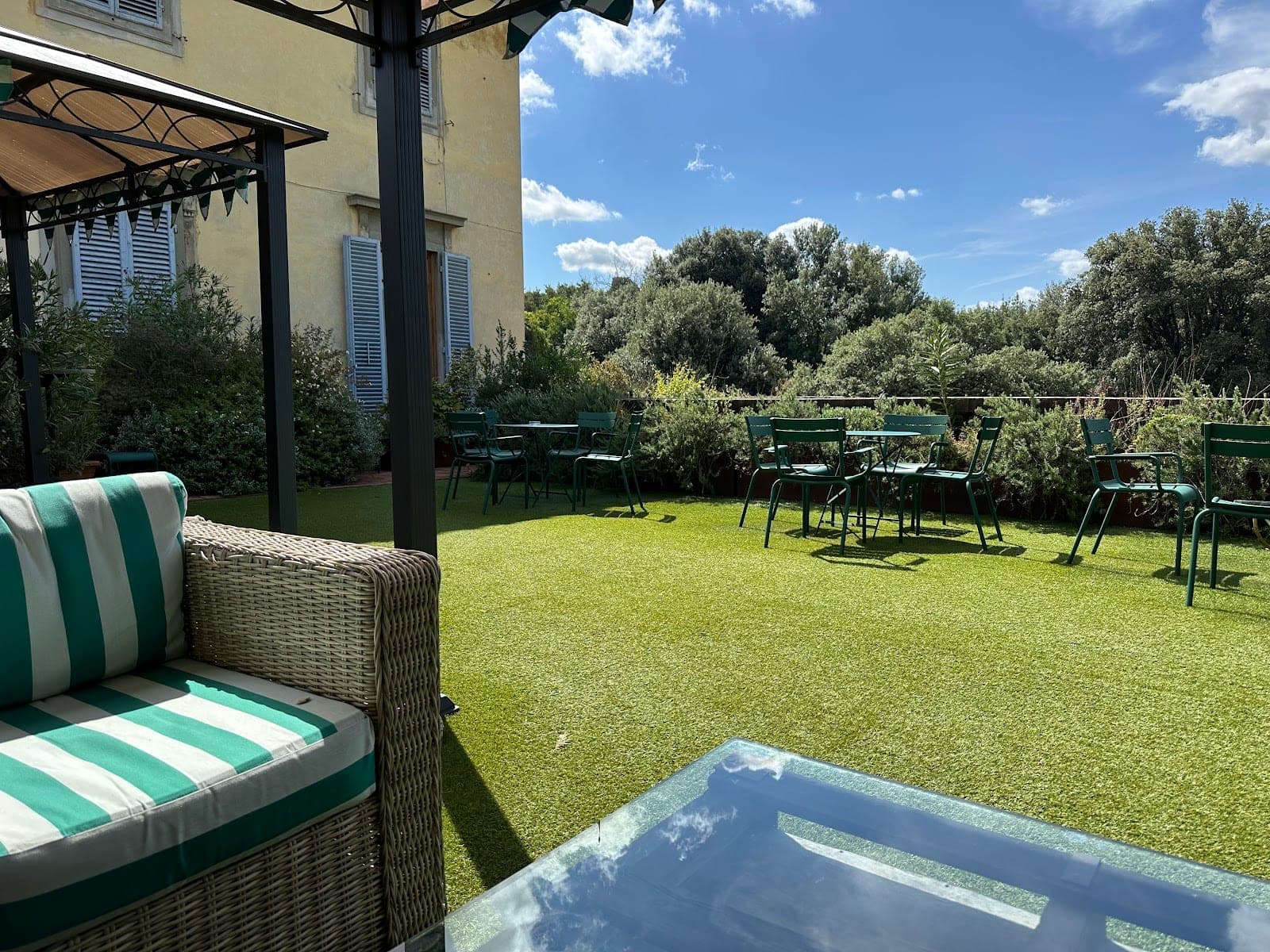 Outdoor seating area with green chairs and tables on artificial grass