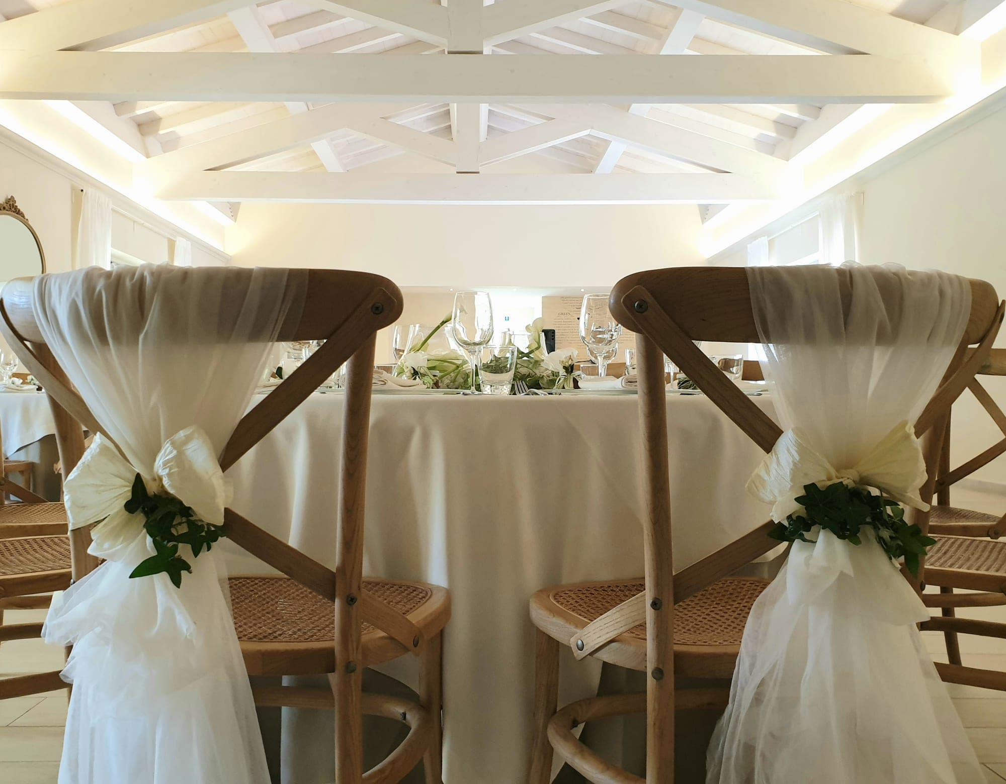 Wedding reception table setting with decorated chairs.