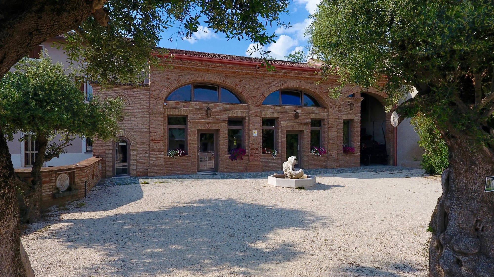 Exterior of a brick building with arched windows and a courtyard with a fountain.