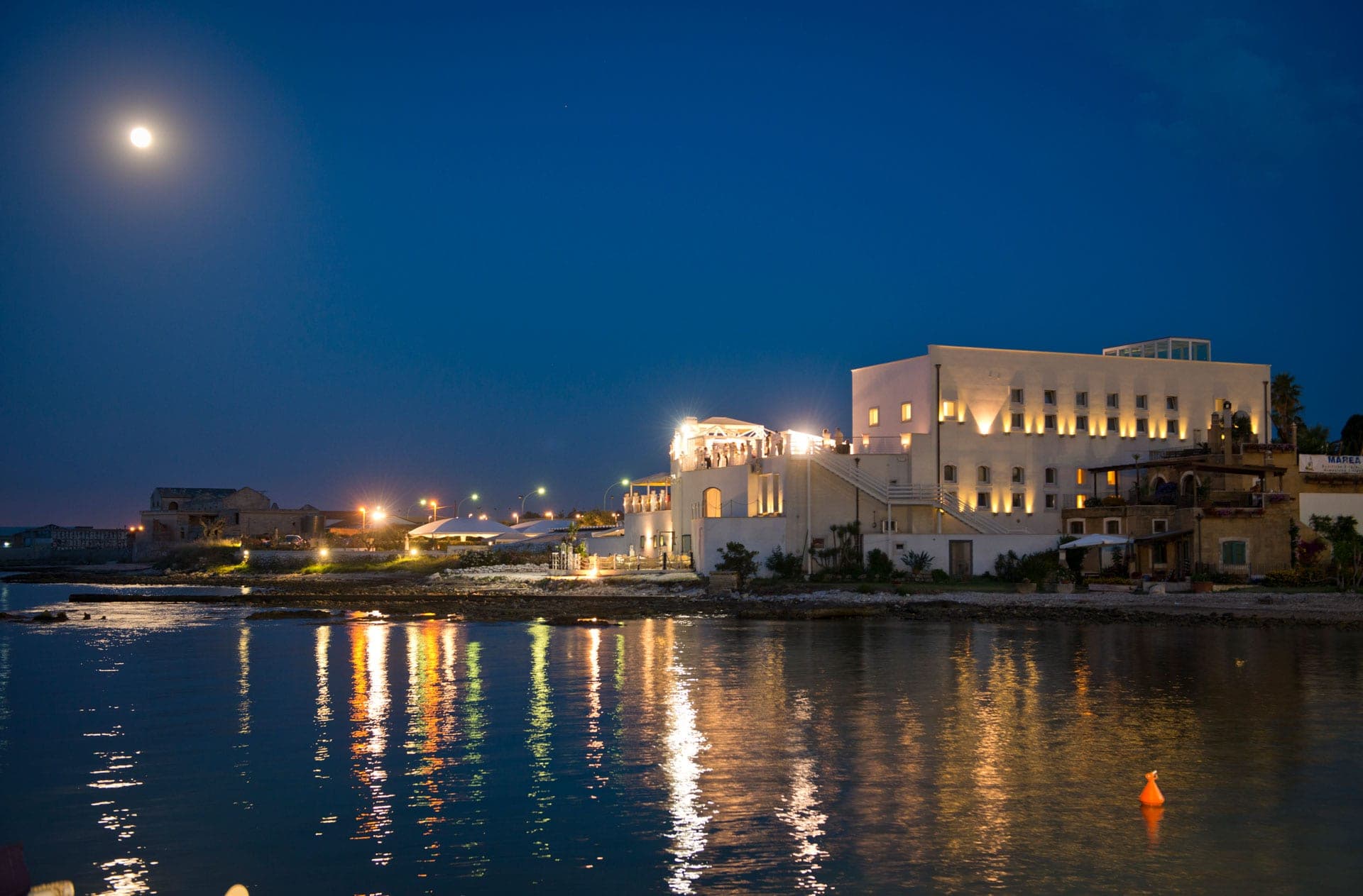 Alsole resort at night with lights reflecting on the water.