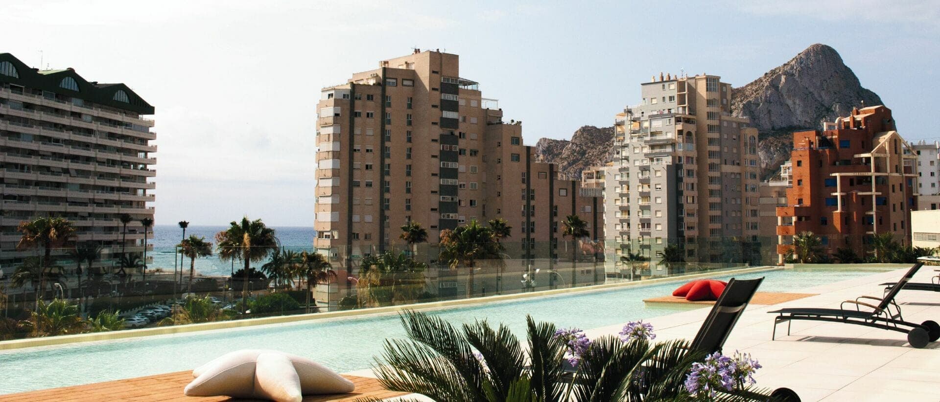 A swimming pool with lounge chairs and buildings in the background.
